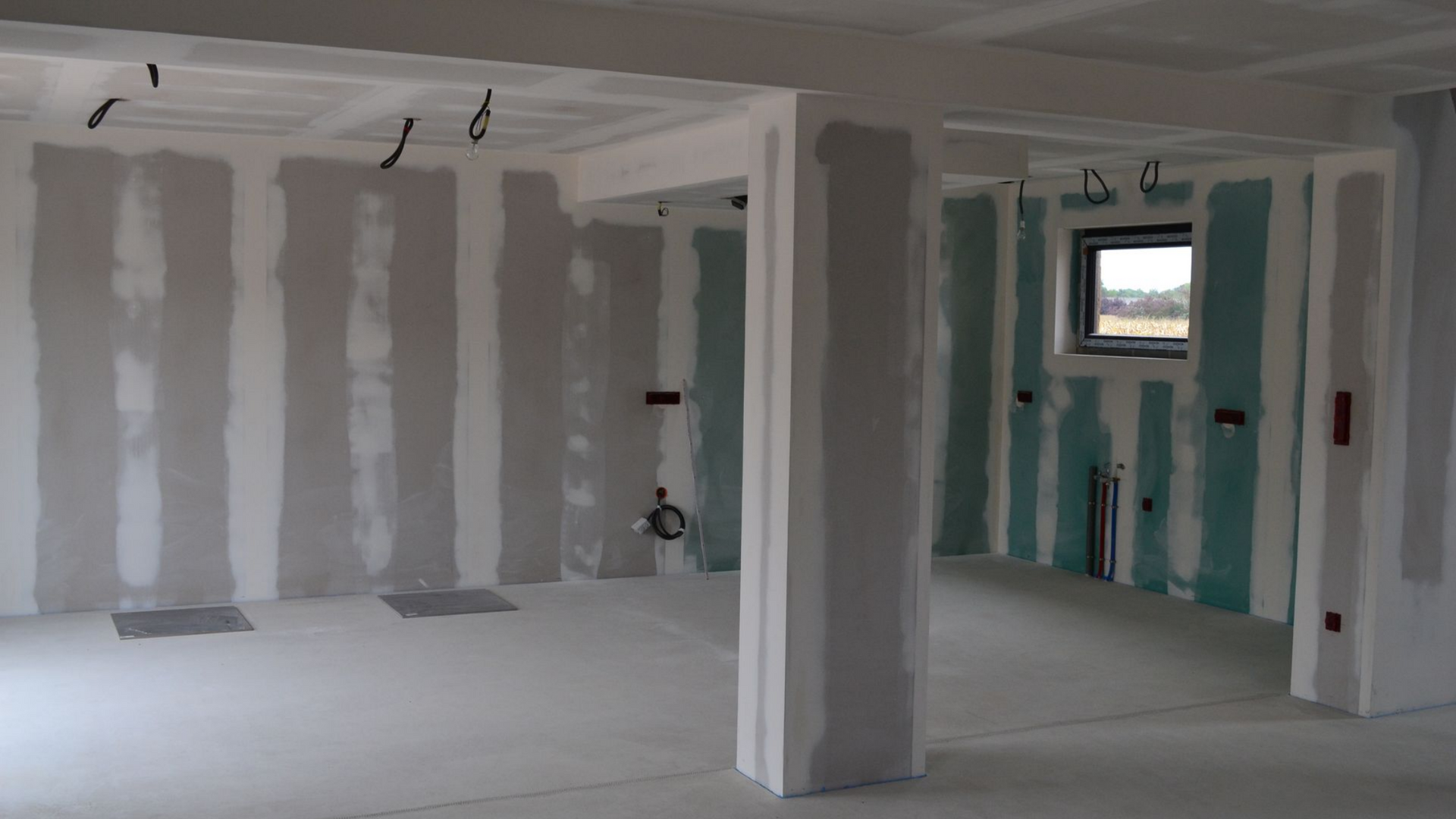 Intérieur d'une pièce en construction avec cloisons sèches et câblage électrique apparents.