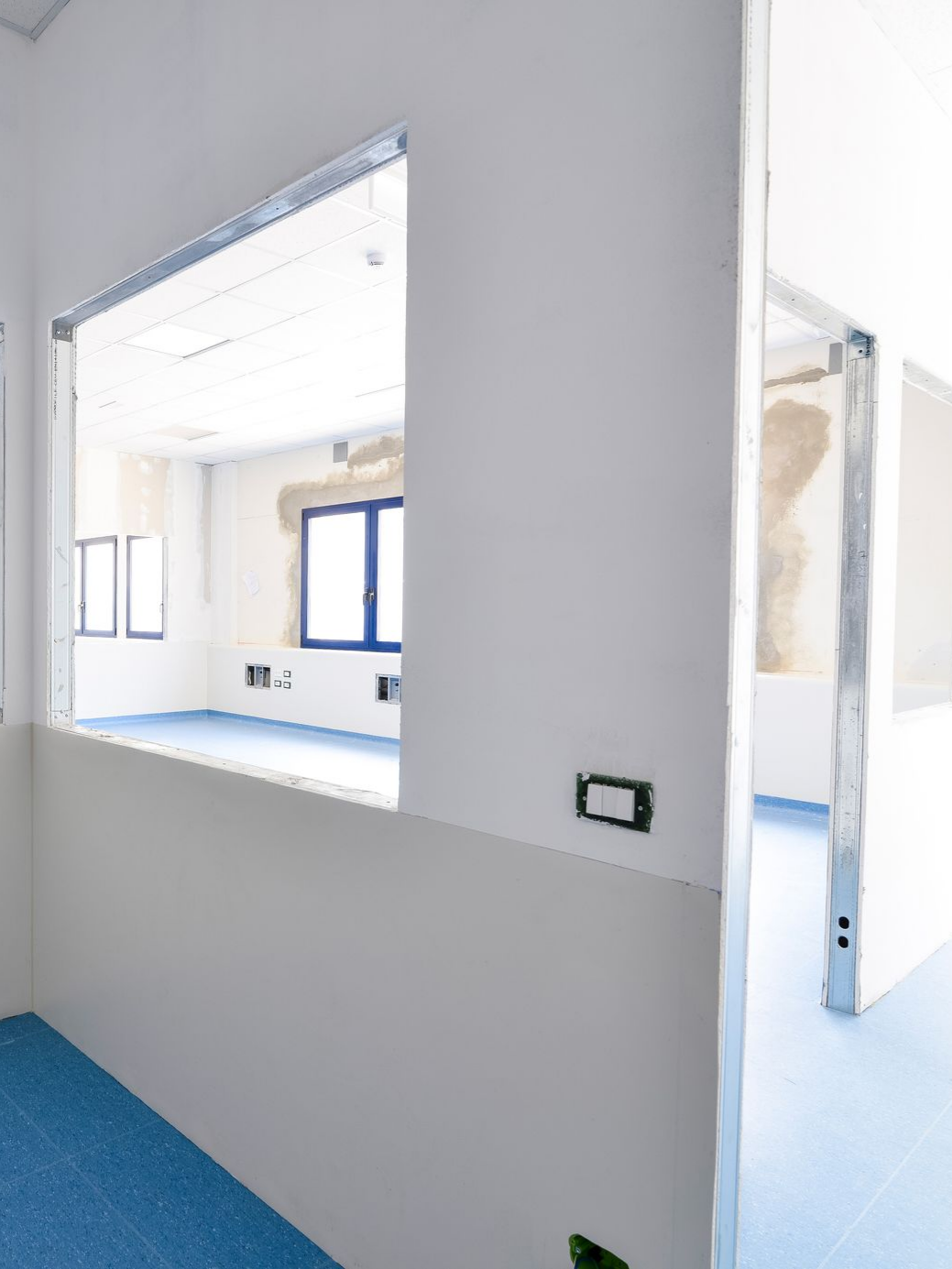 Murs blancs avec une ouverture donnant sur une pièce au sol bleu.