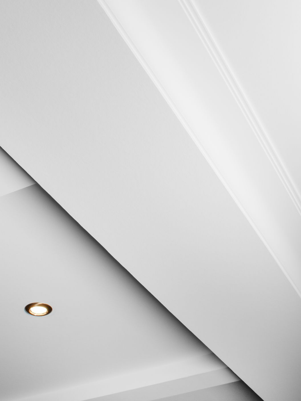 Plafond blanc avec éclairage encastré et moulures décoratives.