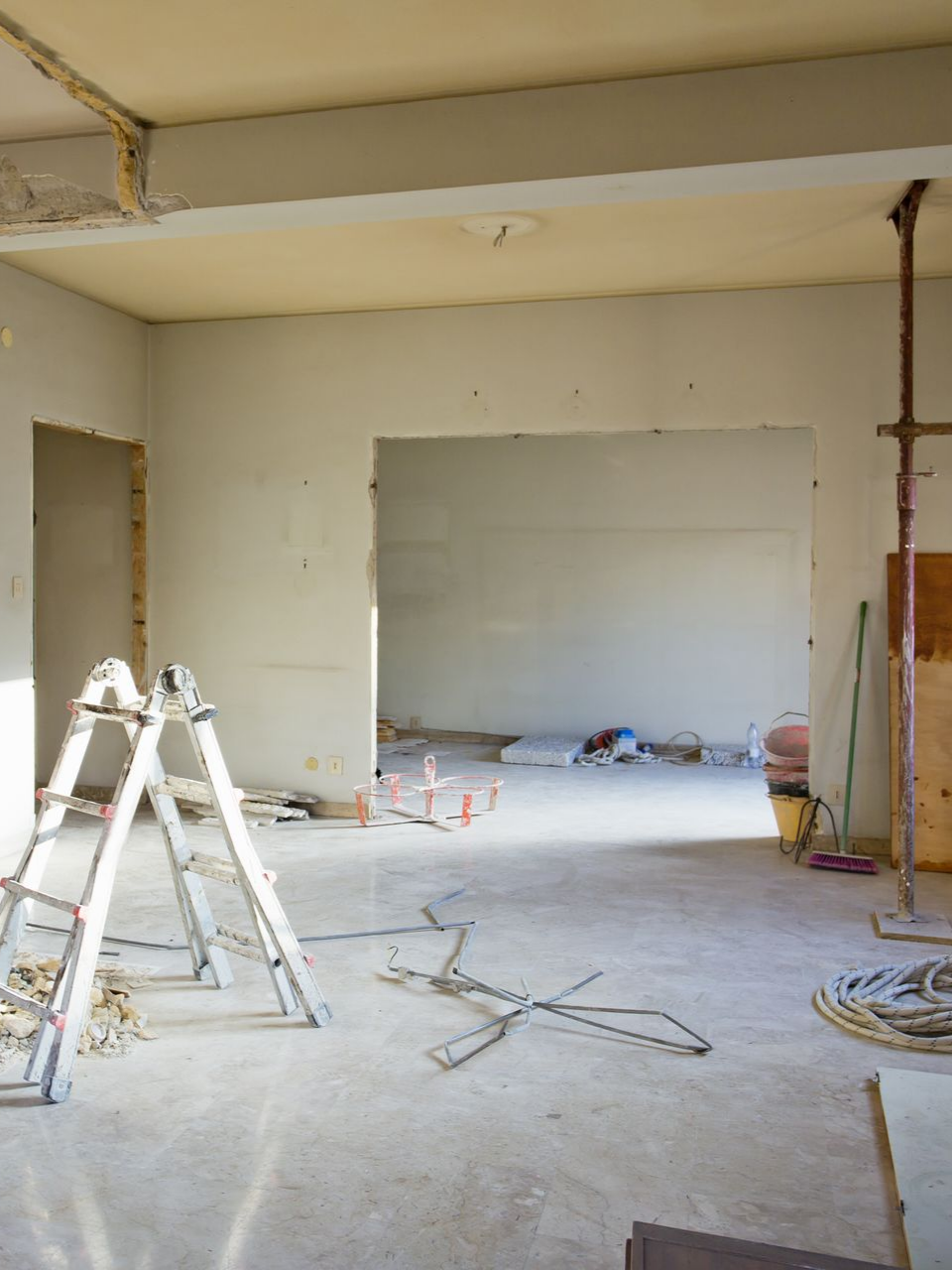 Pièce intérieure en travaux avec échelles, fils électriques apparents et ouvertures de portes.