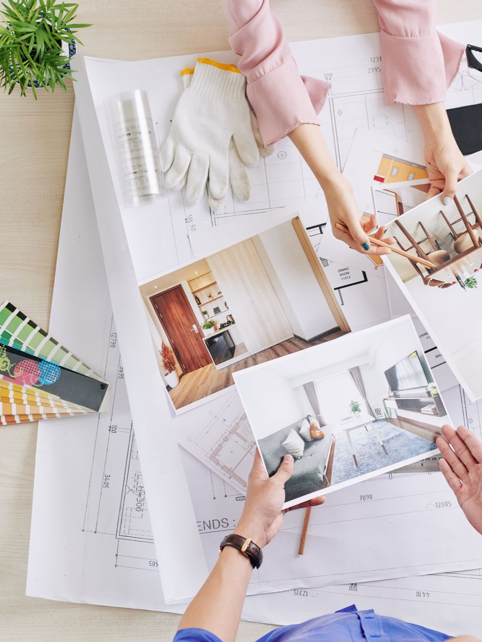 Des mains qui tiennent une photo d'inspiration en décoration intérieure posée sur des plans.