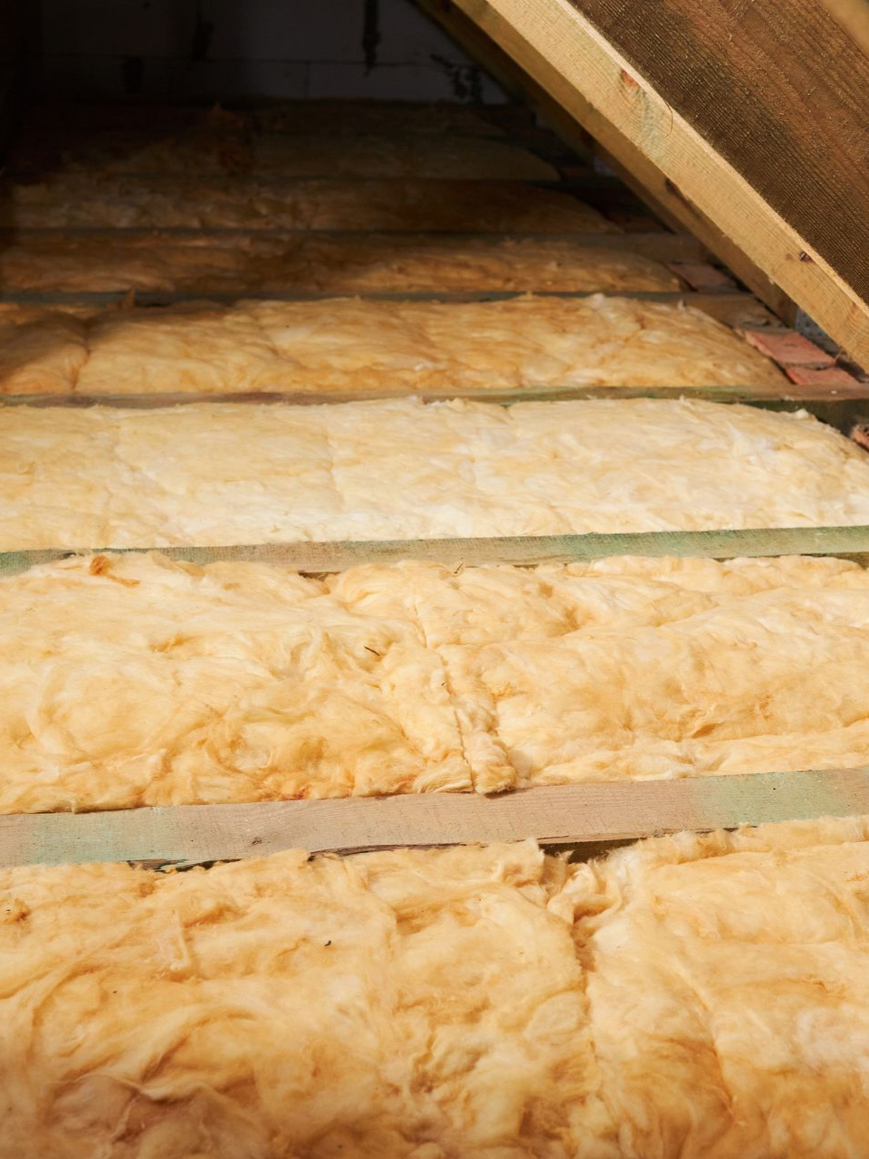 Des panneaux isolants jaunes sont installés entre les chevrons en bois.