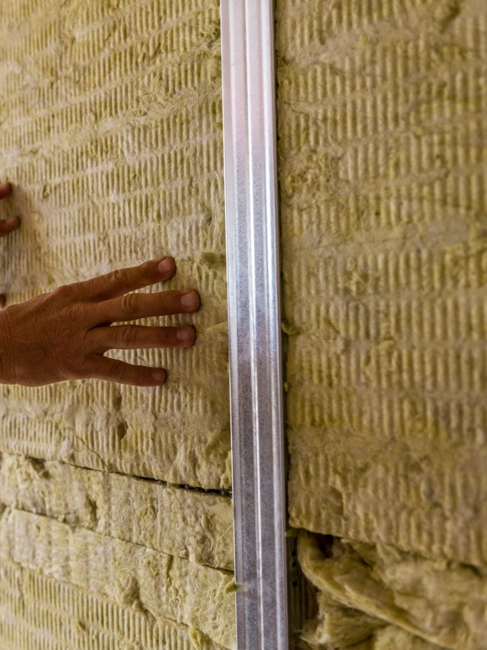 Pose de panneaux isolants sur le mur, à côté du montant métallique.