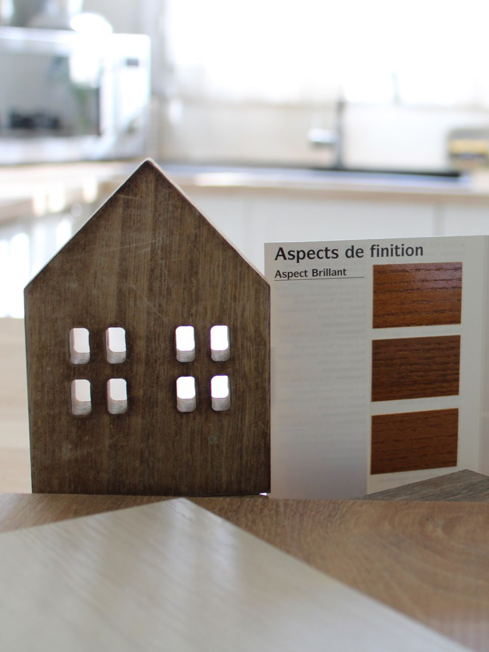 Maquette de maison en bois avec échantillons de finitions sur une table.