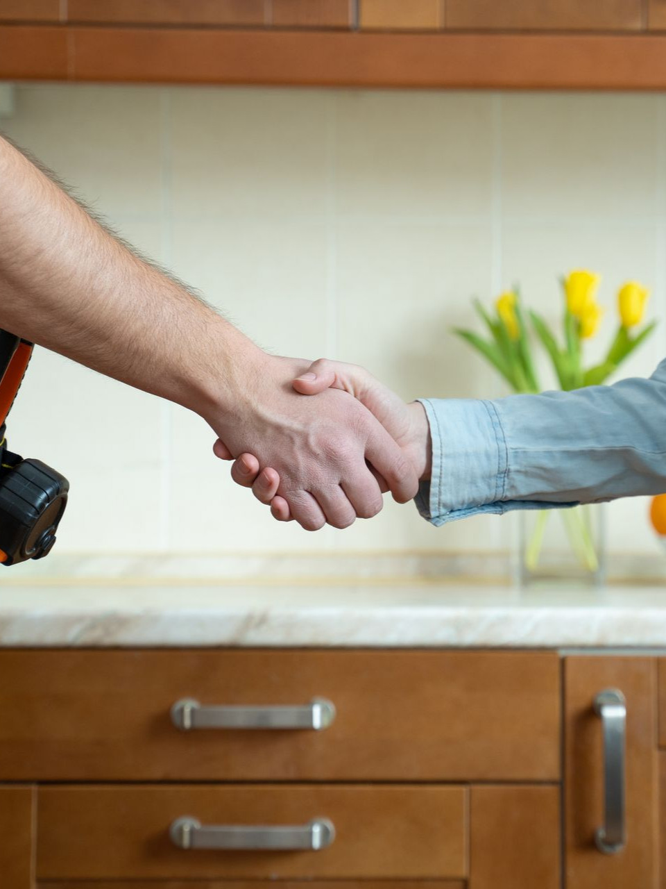 Deux personnes se serrent la main au-dessus d'un comptoir de cuisine.