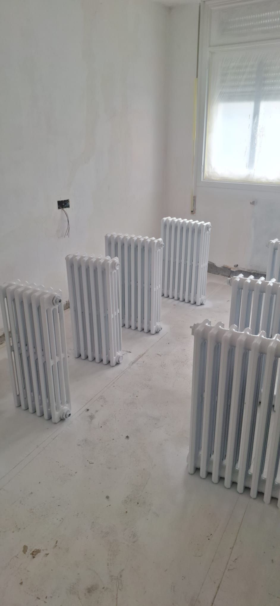 Una habitación con muchos radiadores blancos en el suelo.
