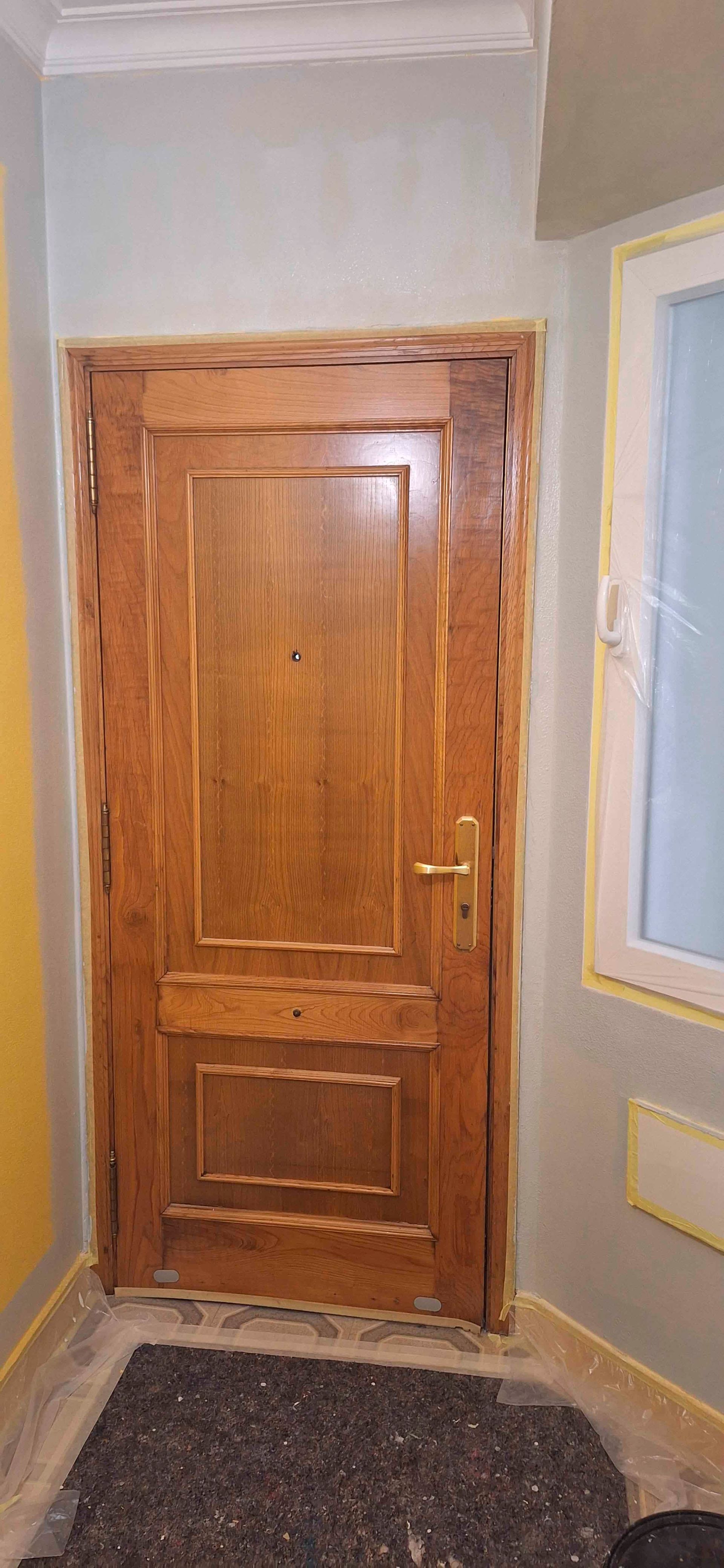Una puerta de madera está en una habitación al lado de una ventana.