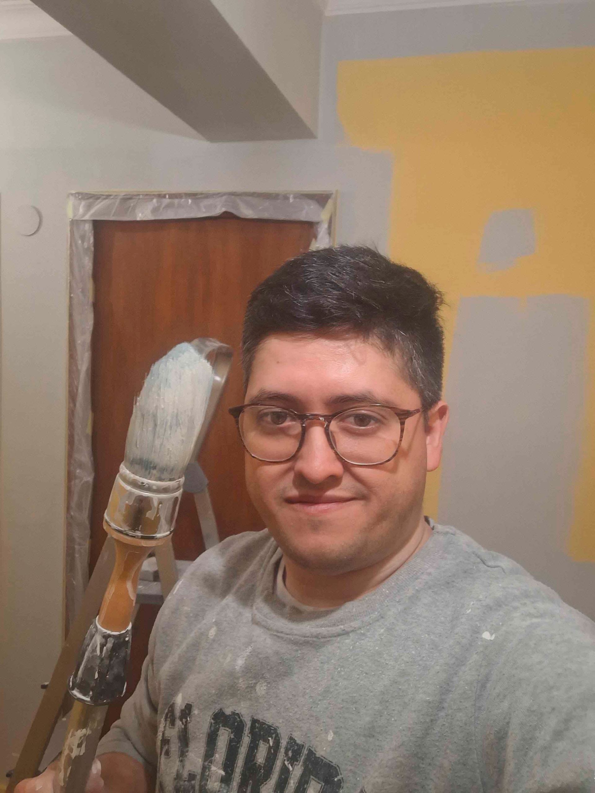 Un hombre con gafas sostiene un pincel.