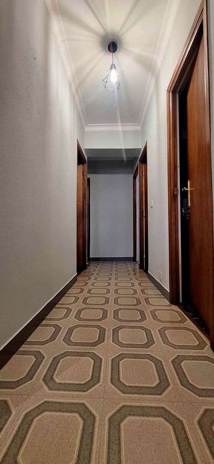 Un pasillo largo con una alfombra estampada y una luz en el techo.