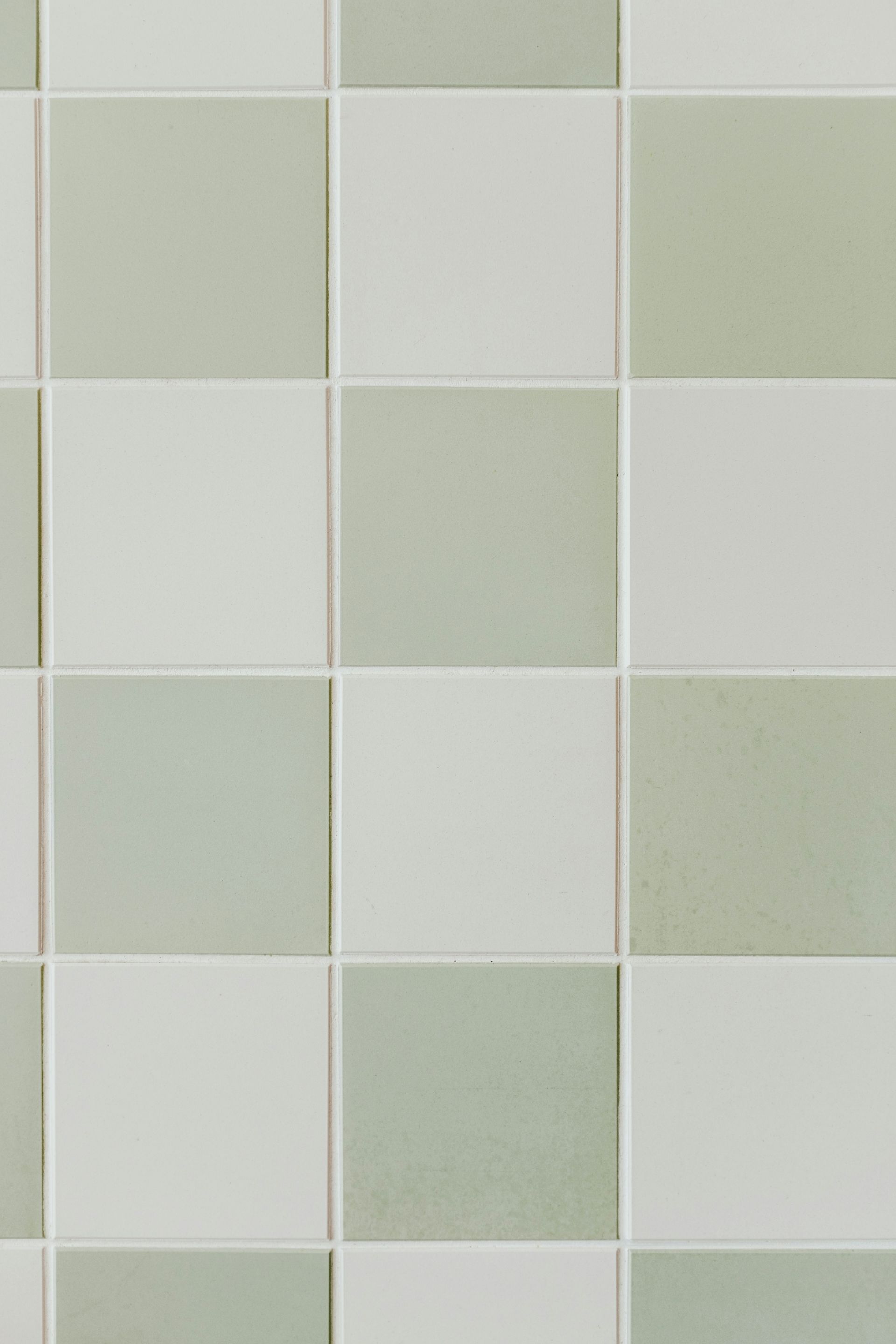 Un primer plano de una pared de azulejos a cuadros blancos y verdes.
