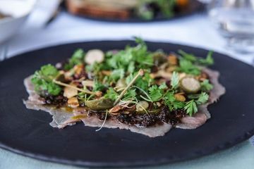 Ein schwarzer Teller mit Fleisch und Gemüse auf einem Tisch.