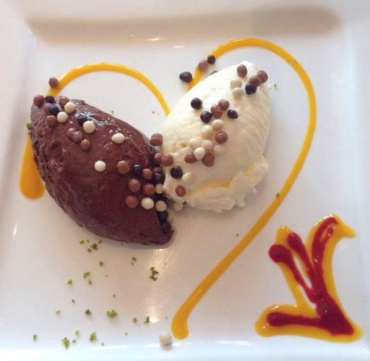 Zwei Kugeln Schokolade und Vanilleeis auf einem weissen Teller