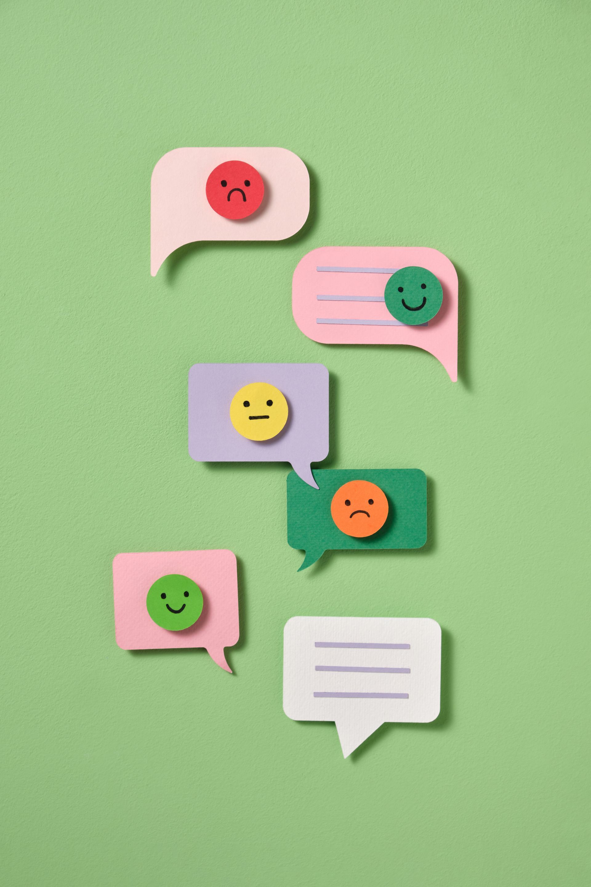 Bulles de discussion colorées avec des émoticônes variées sur fond vert