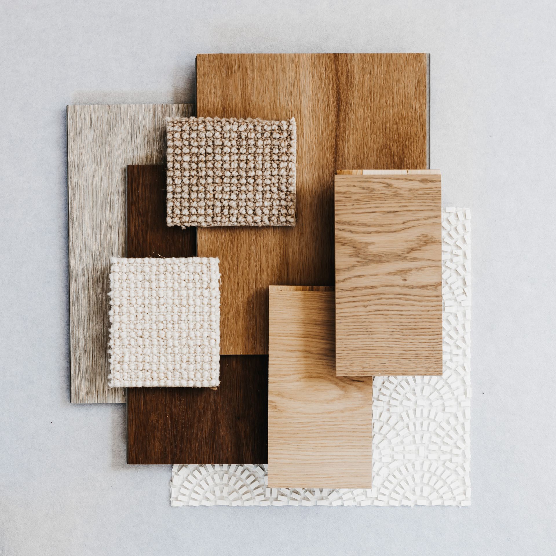 Échantillons de textures de bois et de tissu assortis, disposés en carrés se chevauchant sur un fond clair.