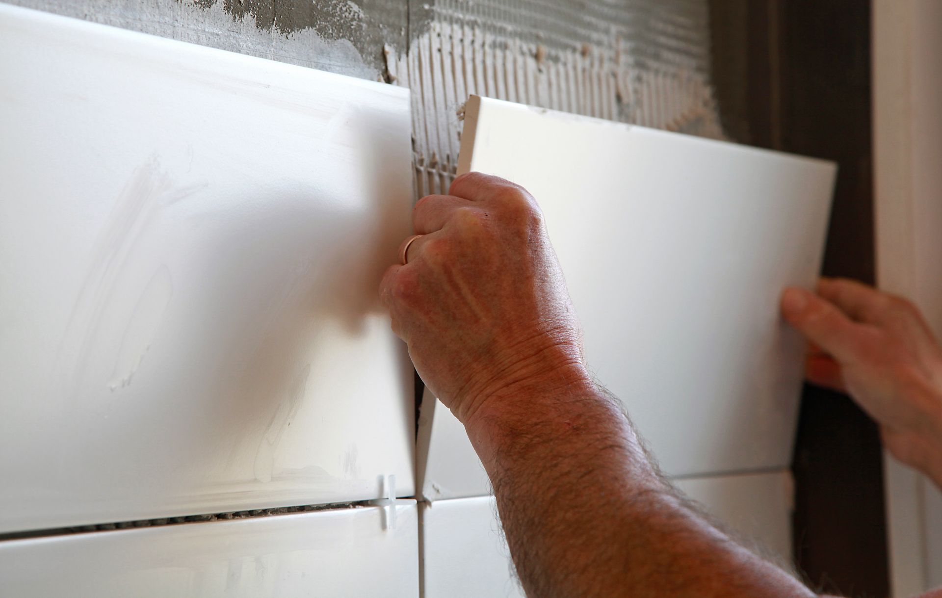 Pose de carreaux muraux blancs à l'aide d'adhésif