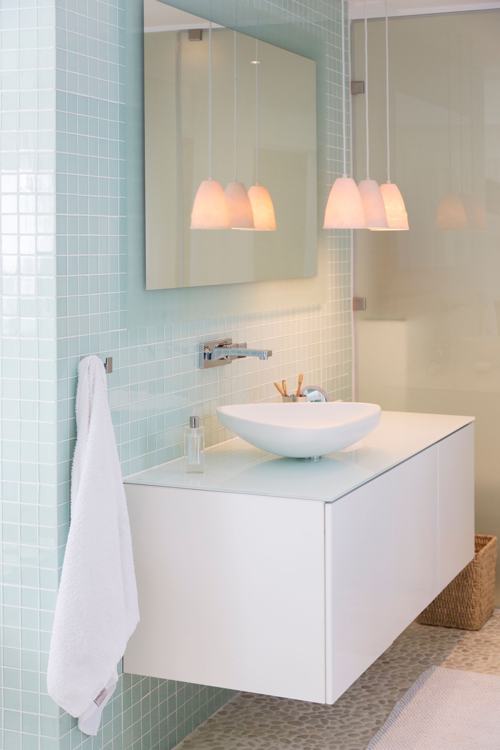 Meuble-lavabo moderne avec miroir mural, lavabo blanc, suspensions lumineuses et mur carrelé bleu clair