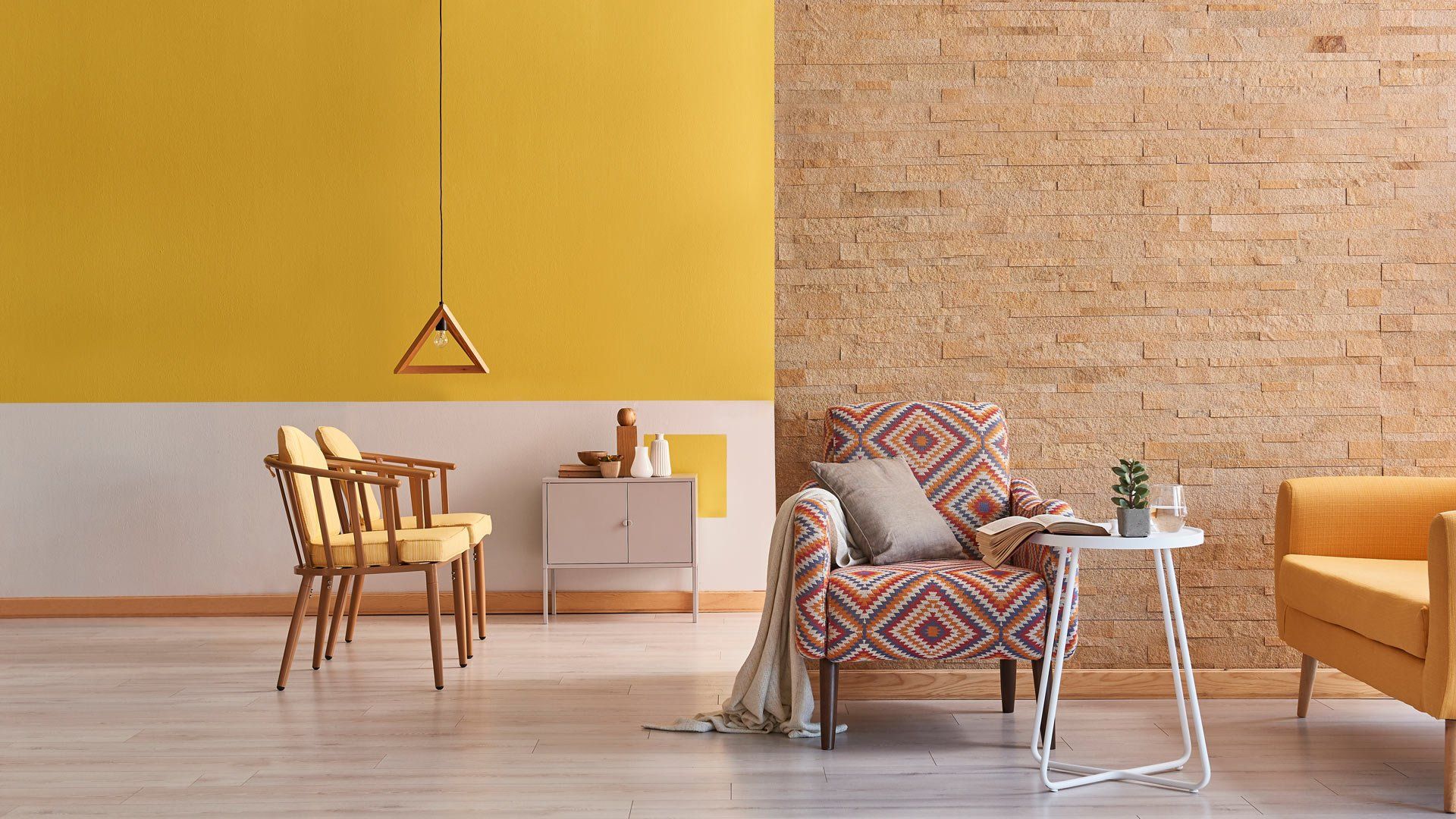 Salon moderne avec mur moutarde, fauteuil à motifs, canapé moutarde, petite table et table d'appoint blanche