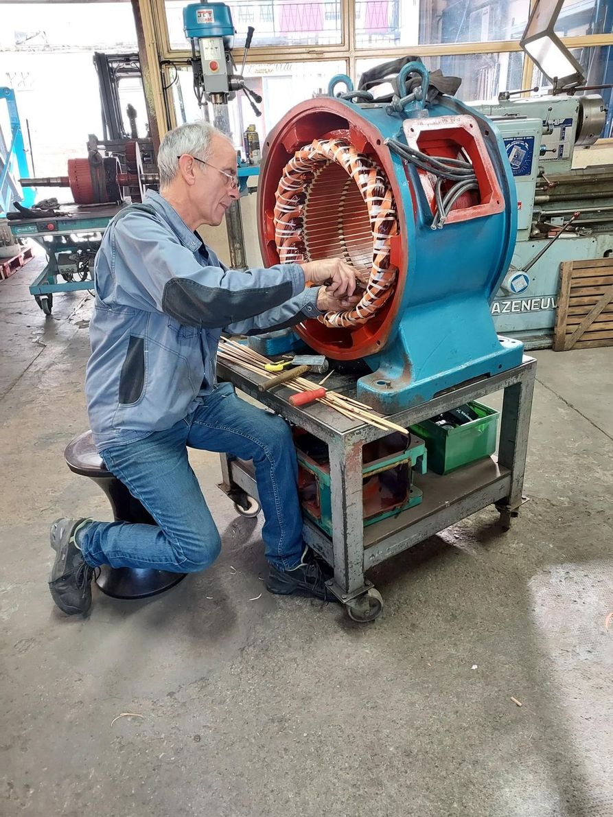 Un homme bricole sur un moteur bleu