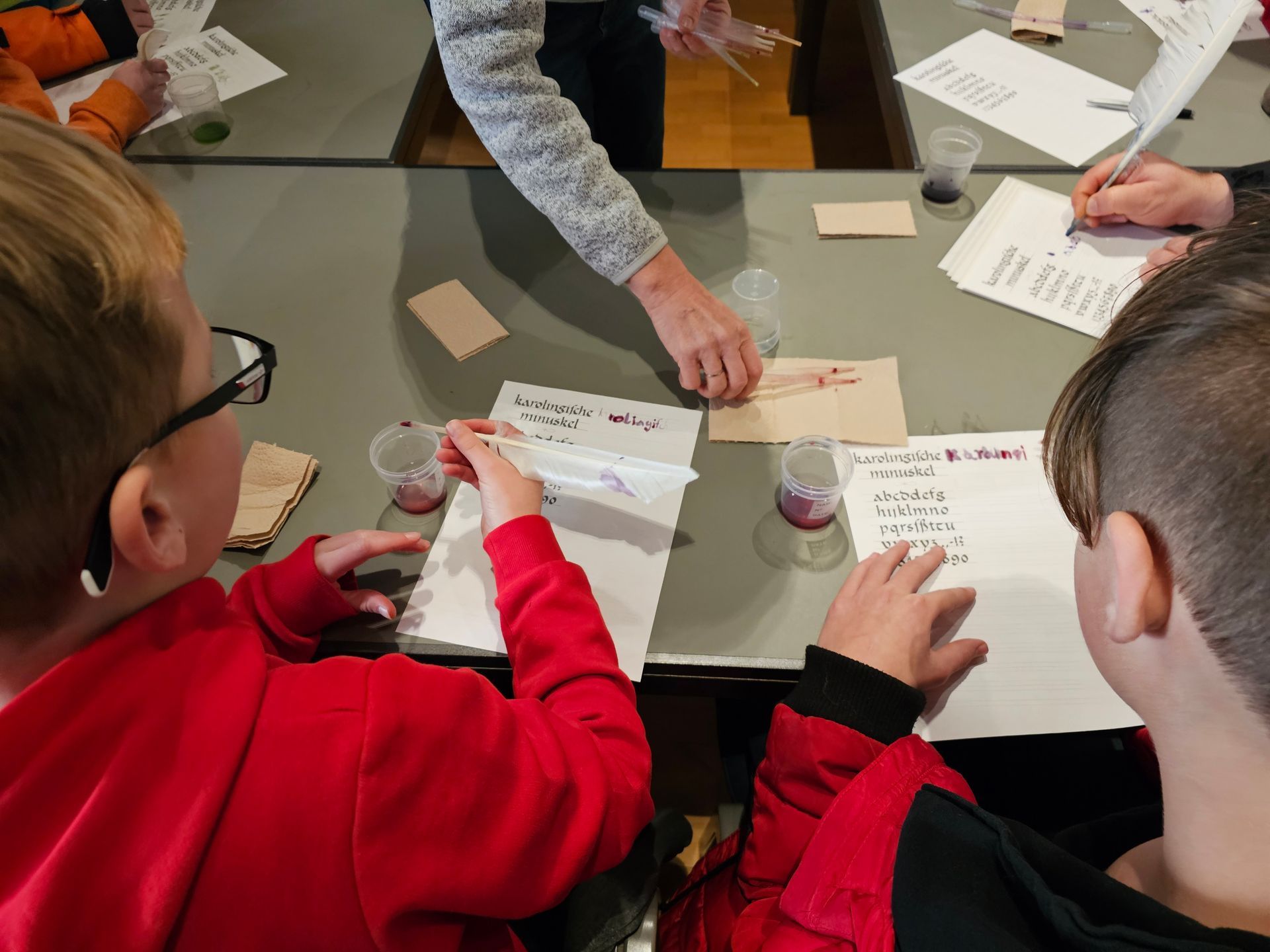 Eine Gruppe Kinder sitzt an einem Tisch und schreibt auf Papier.