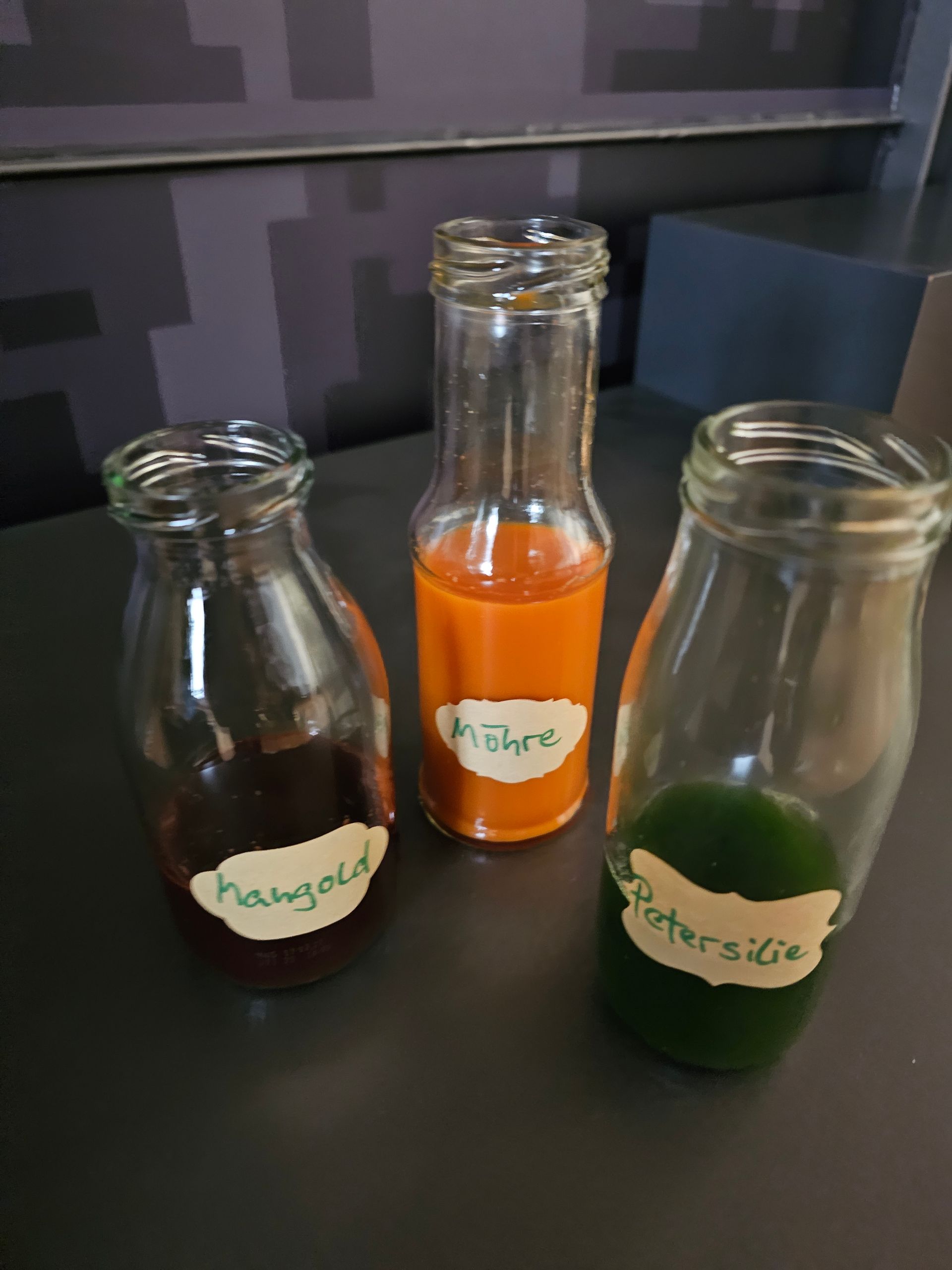 Auf einem Tisch stehen drei Flaschen mit verschiedenfarbigen Flüssigkeiten.