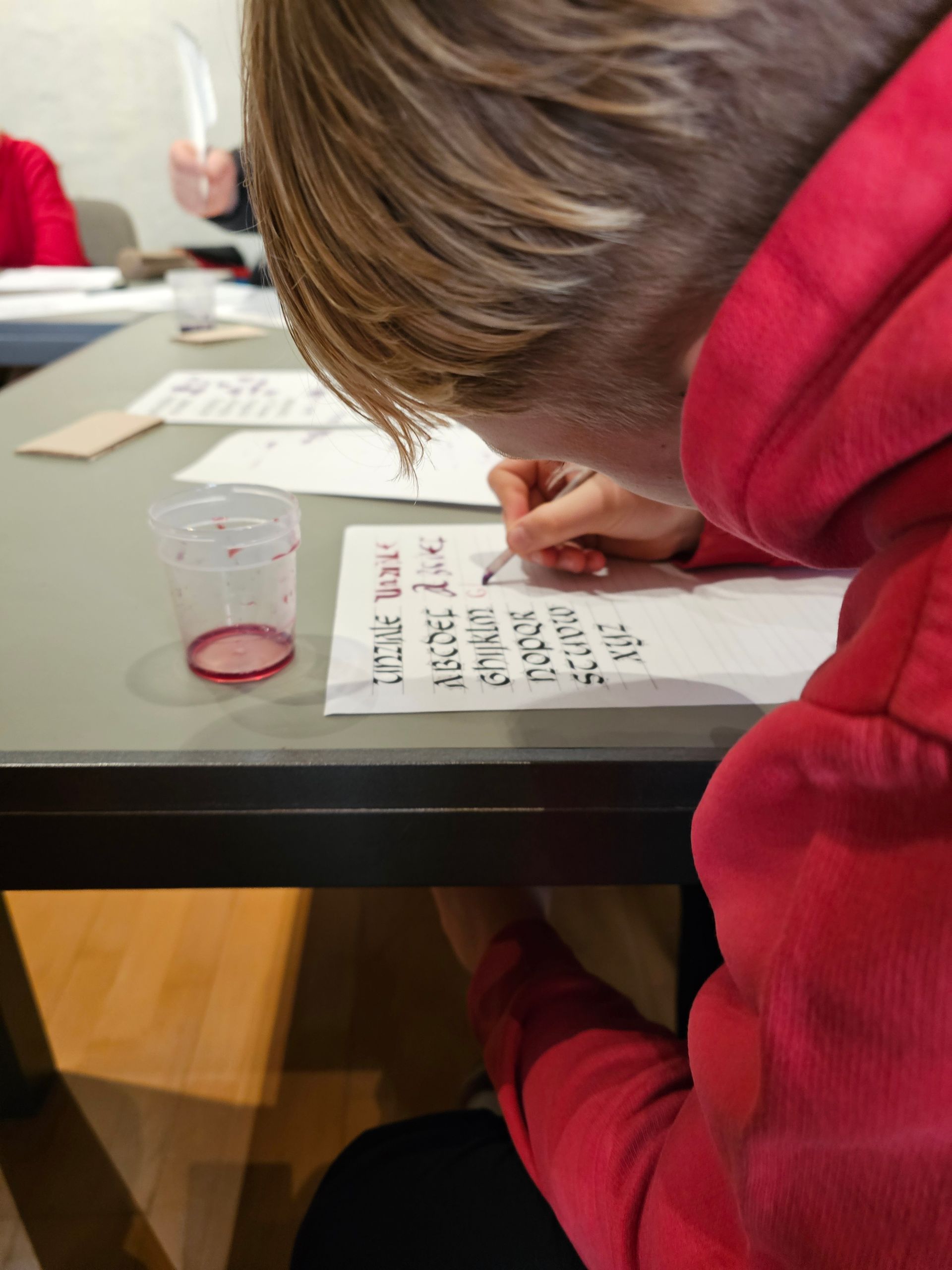 Eine Person in einem roten Kapuzenpullover schreibt auf ein Stück Papier