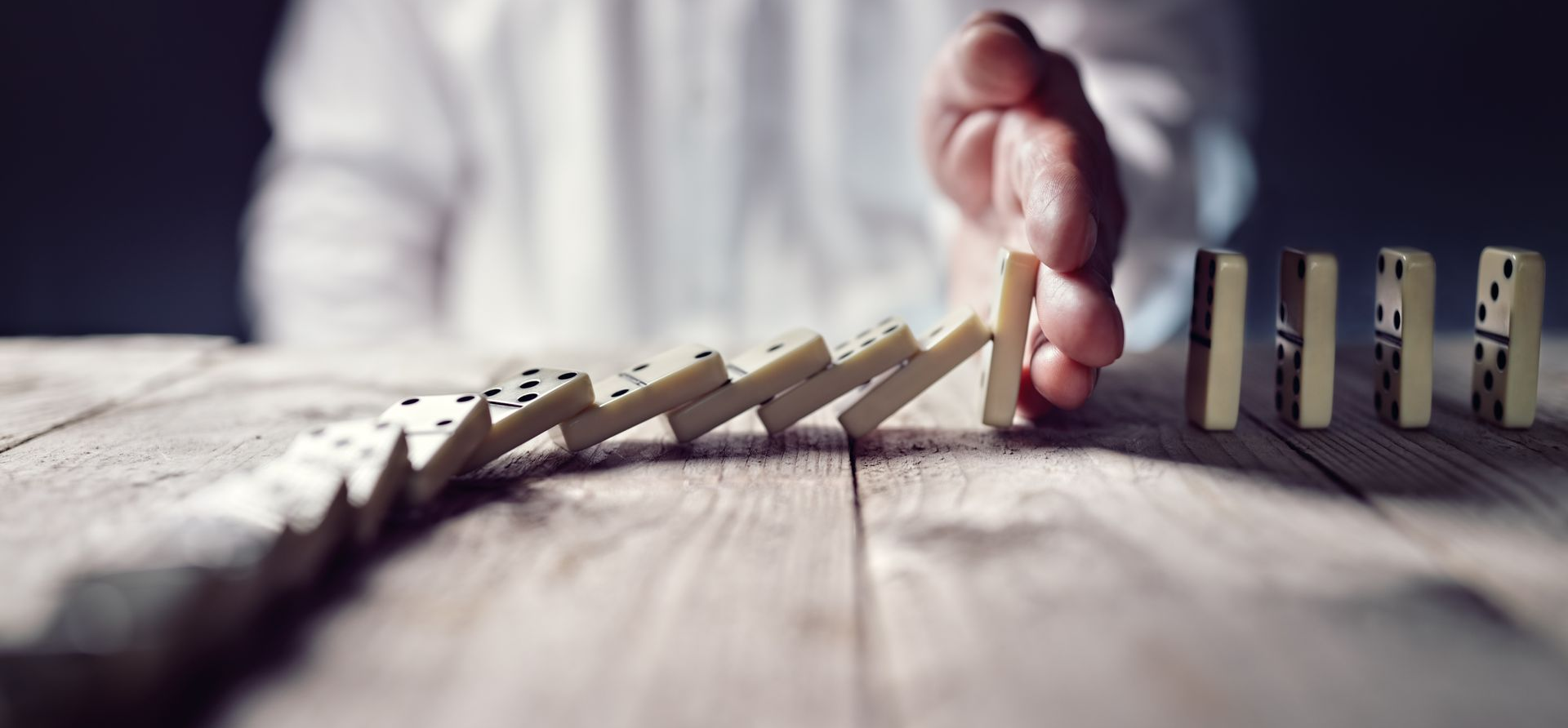 Main stoppant un ensemble de dominos à jouer qui tombent