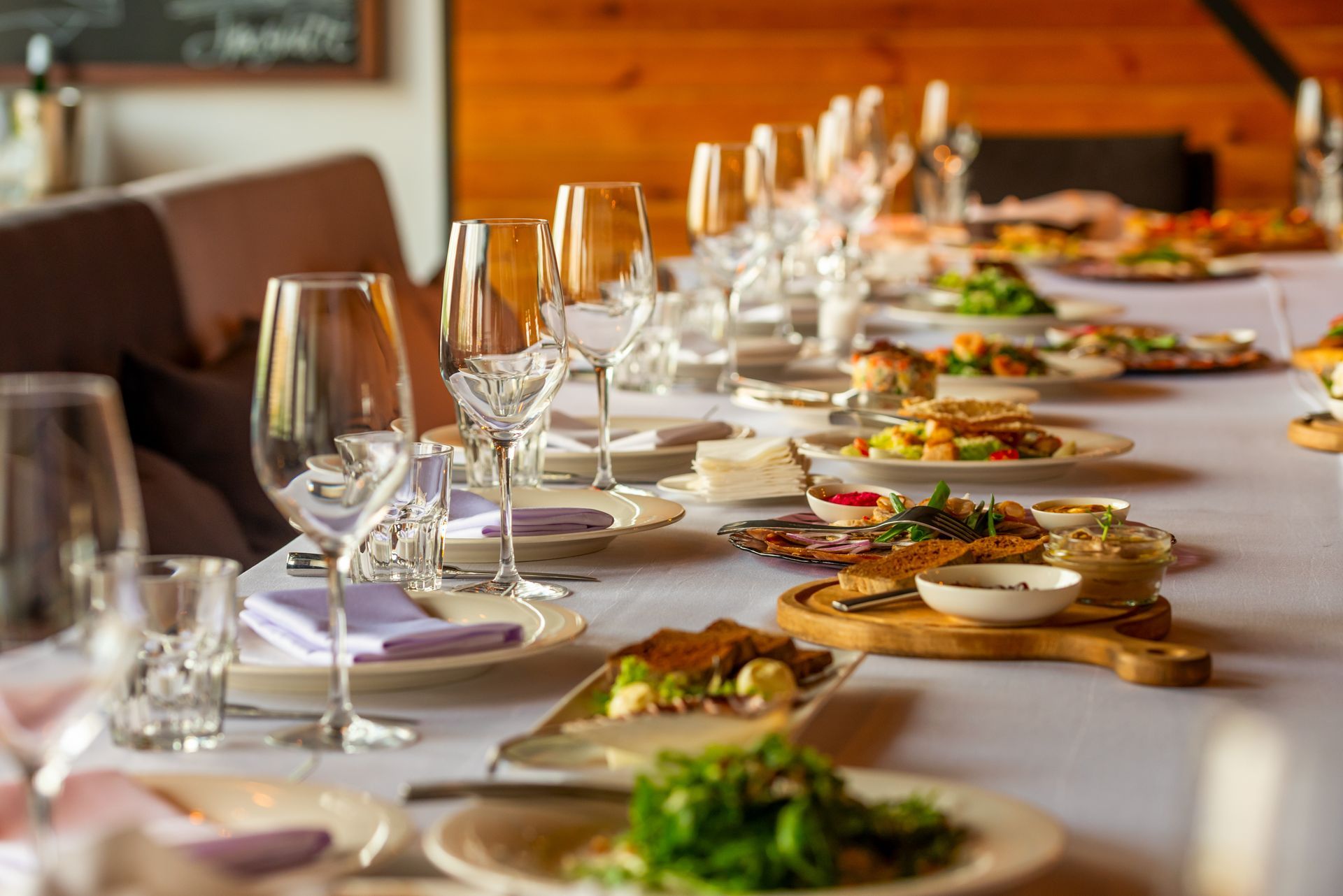 Élégante table de restaurant dressée avec des verres à vin, des assiettes et une nappe blanche.