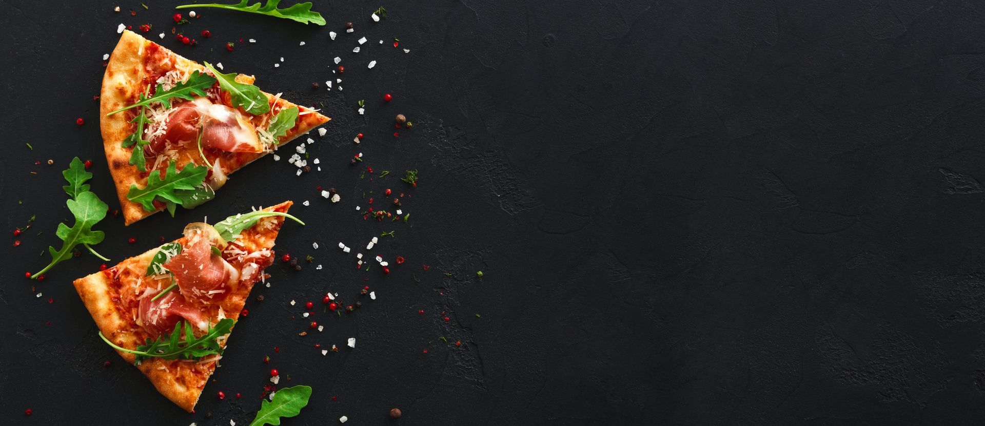 Deux parts de pizza garnies de basilic et de flocons de piment rouge.