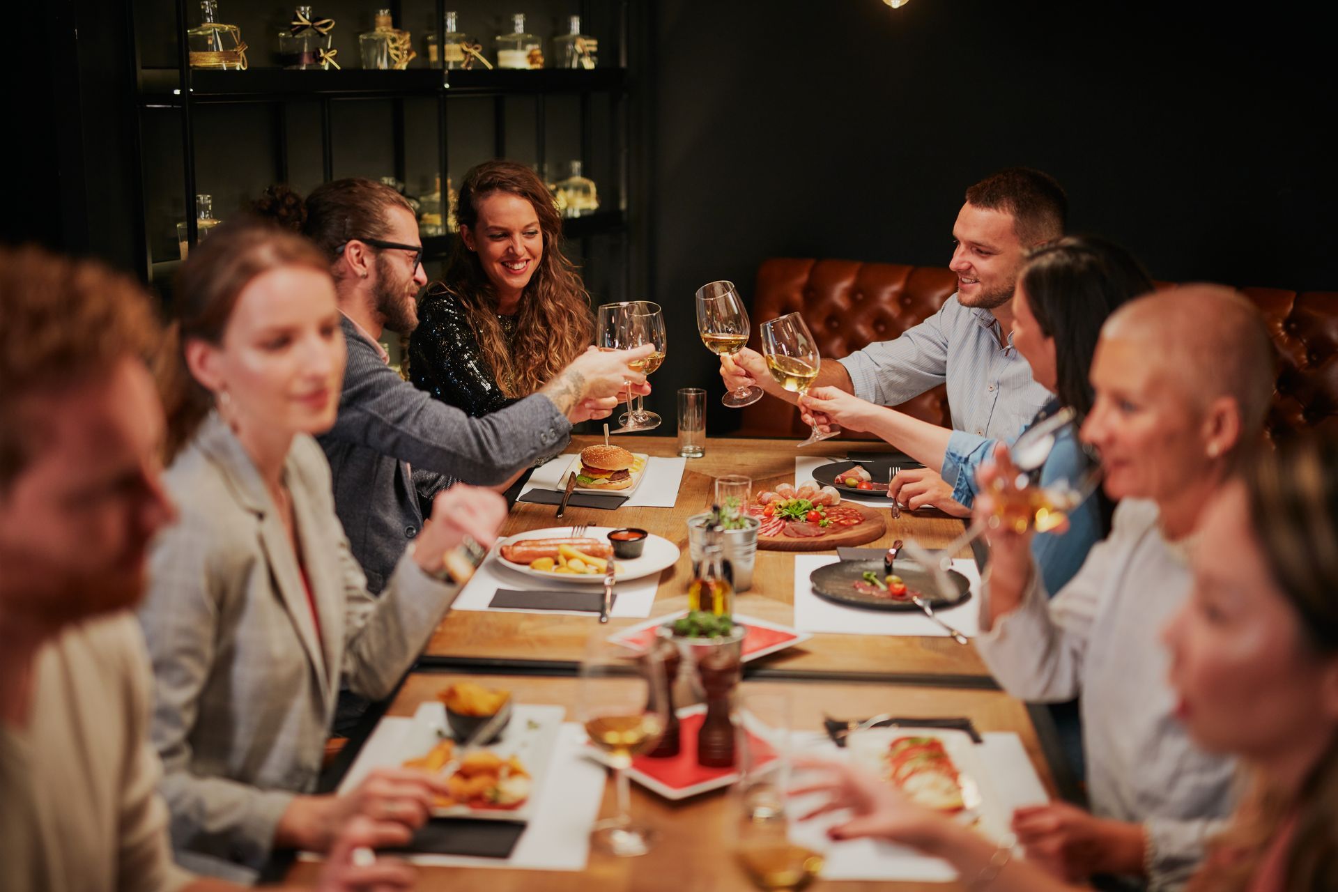 Des amis lèvent leurs verres autour d'une table éclairée aux chandelles dans un restaurant.