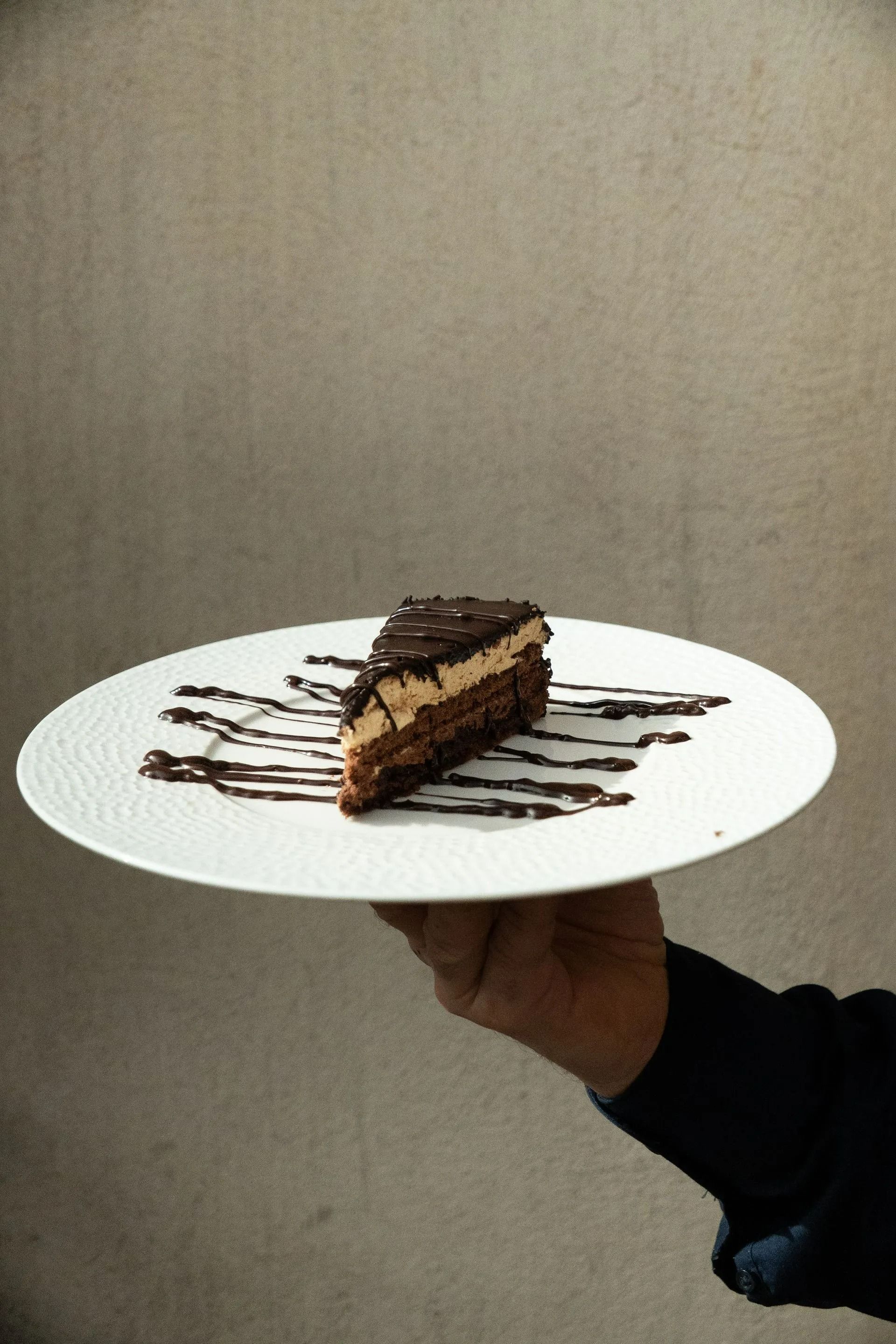 Une part de gâteau au chocolat nappée de chocolat, présentée sur une assiette blanche.