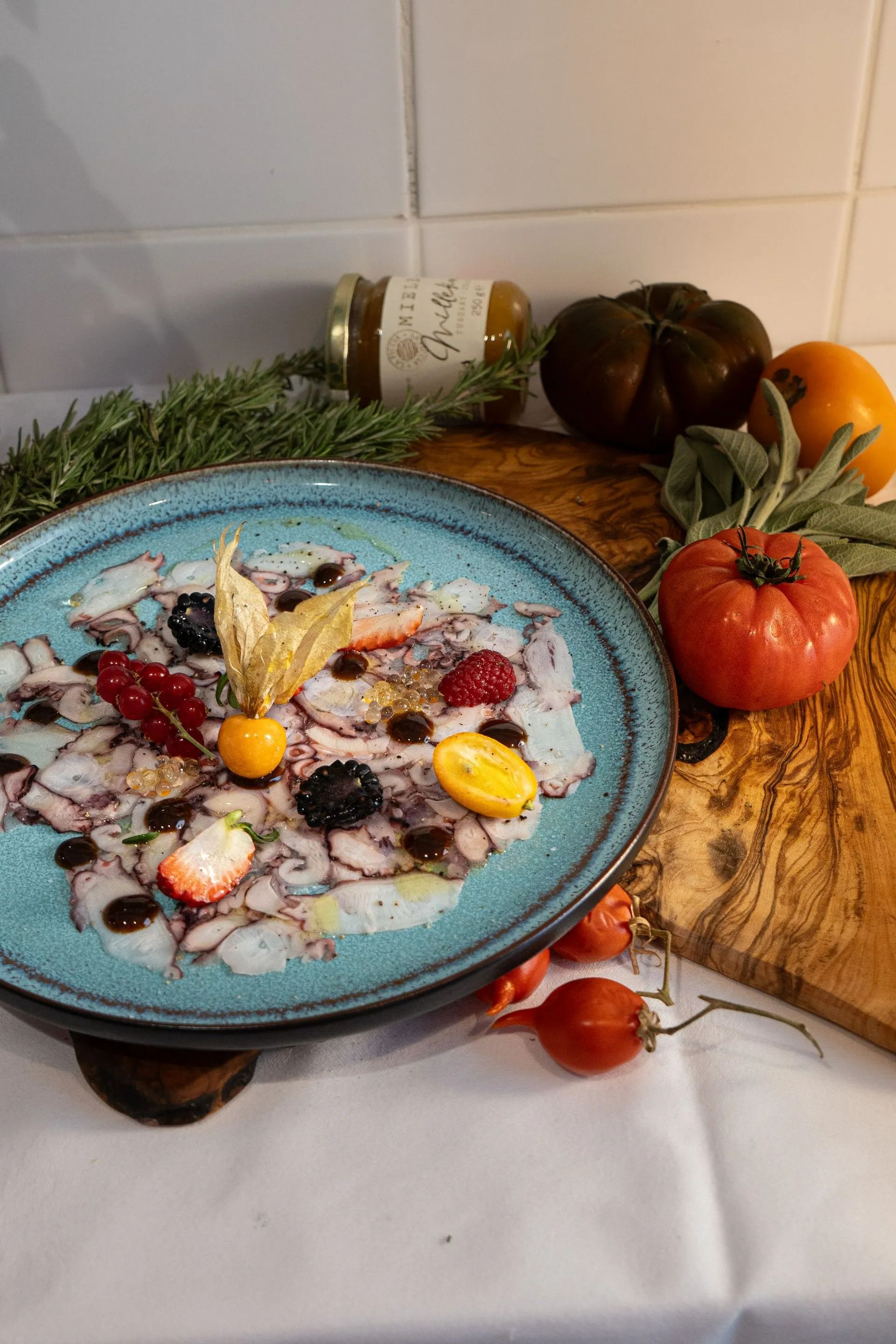 Un bol bleu de dessert crémeux garni de fruits et de noix, posé sur une table décorée de citrouilles et d'éléments de décoration automnale.