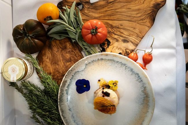 Décoration de table automnale avec des courges, des feuilles, des fleurs et un dessert présenté sur une planche en bois rustique.