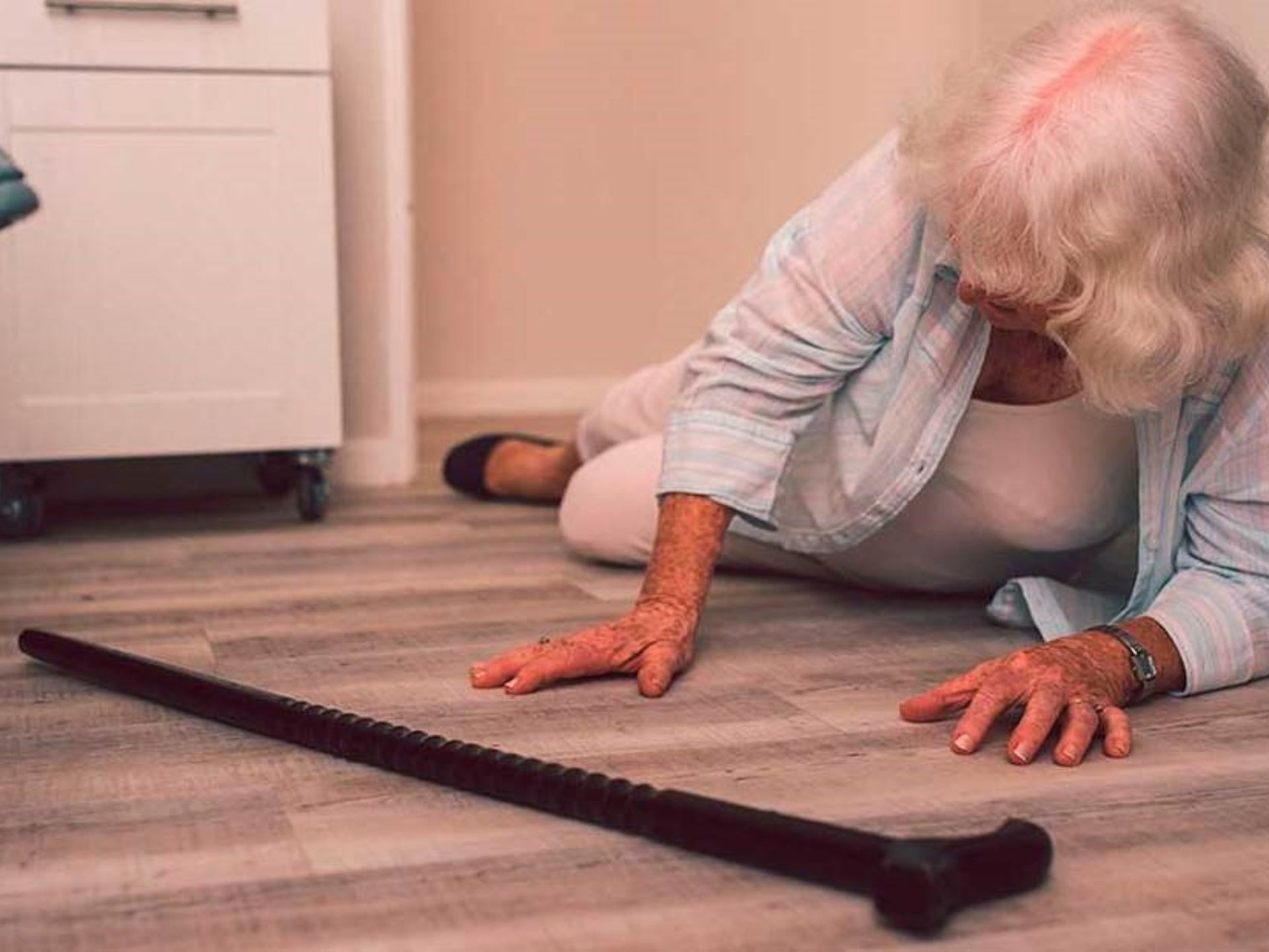 Cuidadora ayuda a una anciana a caminar al aire libre, sonriendo, tomándole la mano y el brazo.