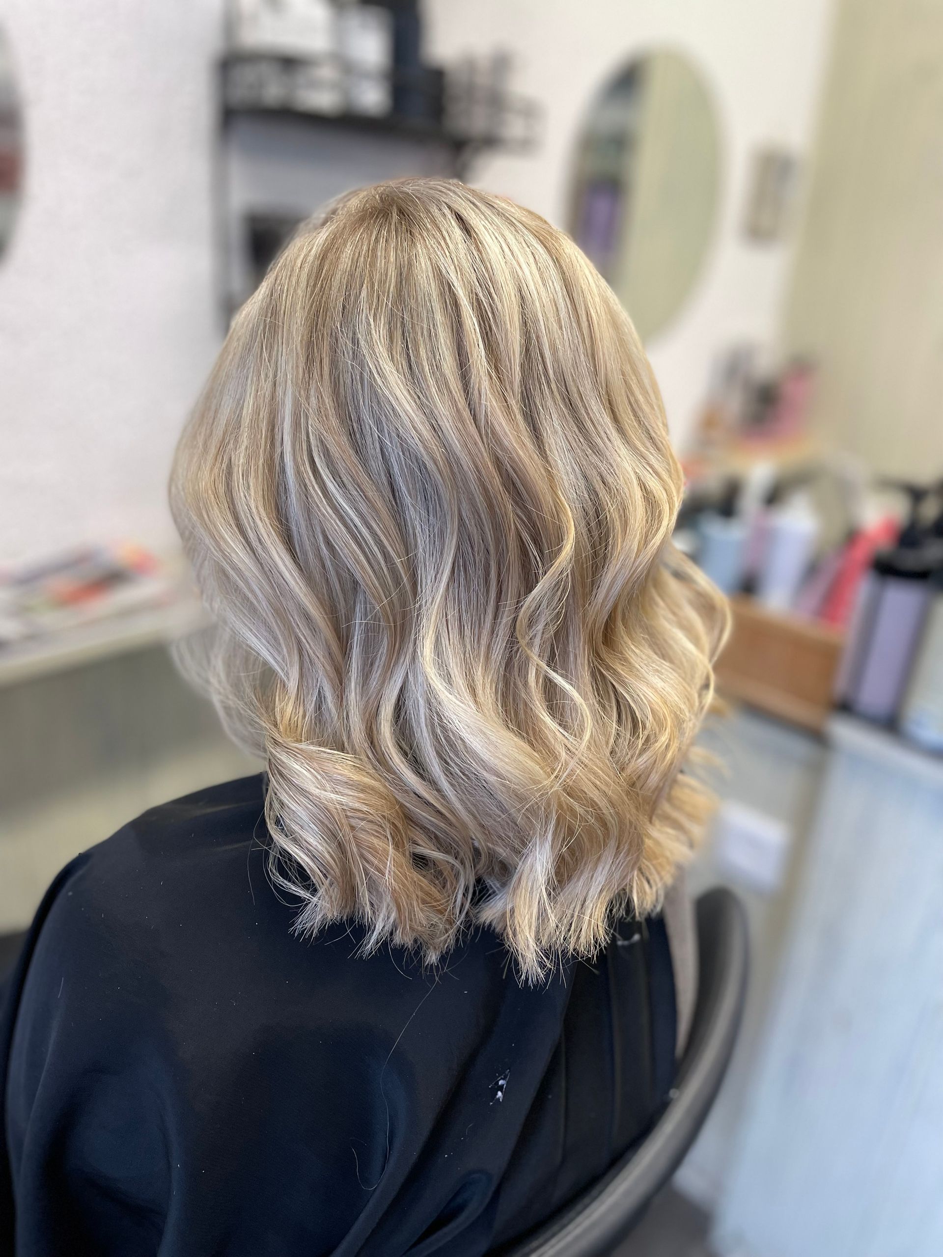 Vue de dos de cheveux blonds ondulés mi-longs sur une chaise de salon