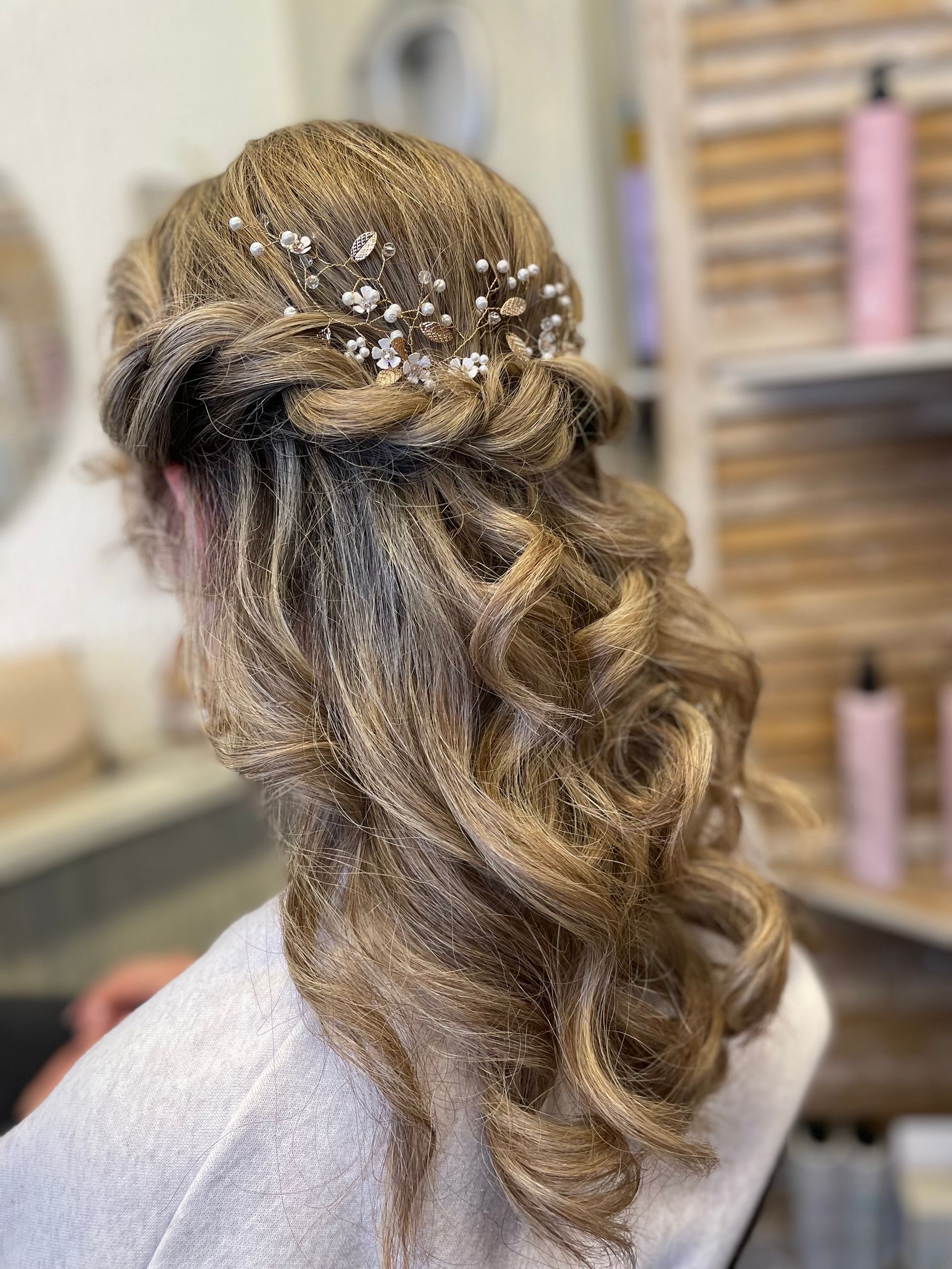 Chignon tressé avec boucles en cascade et reflets dorés dans un cadre de salon