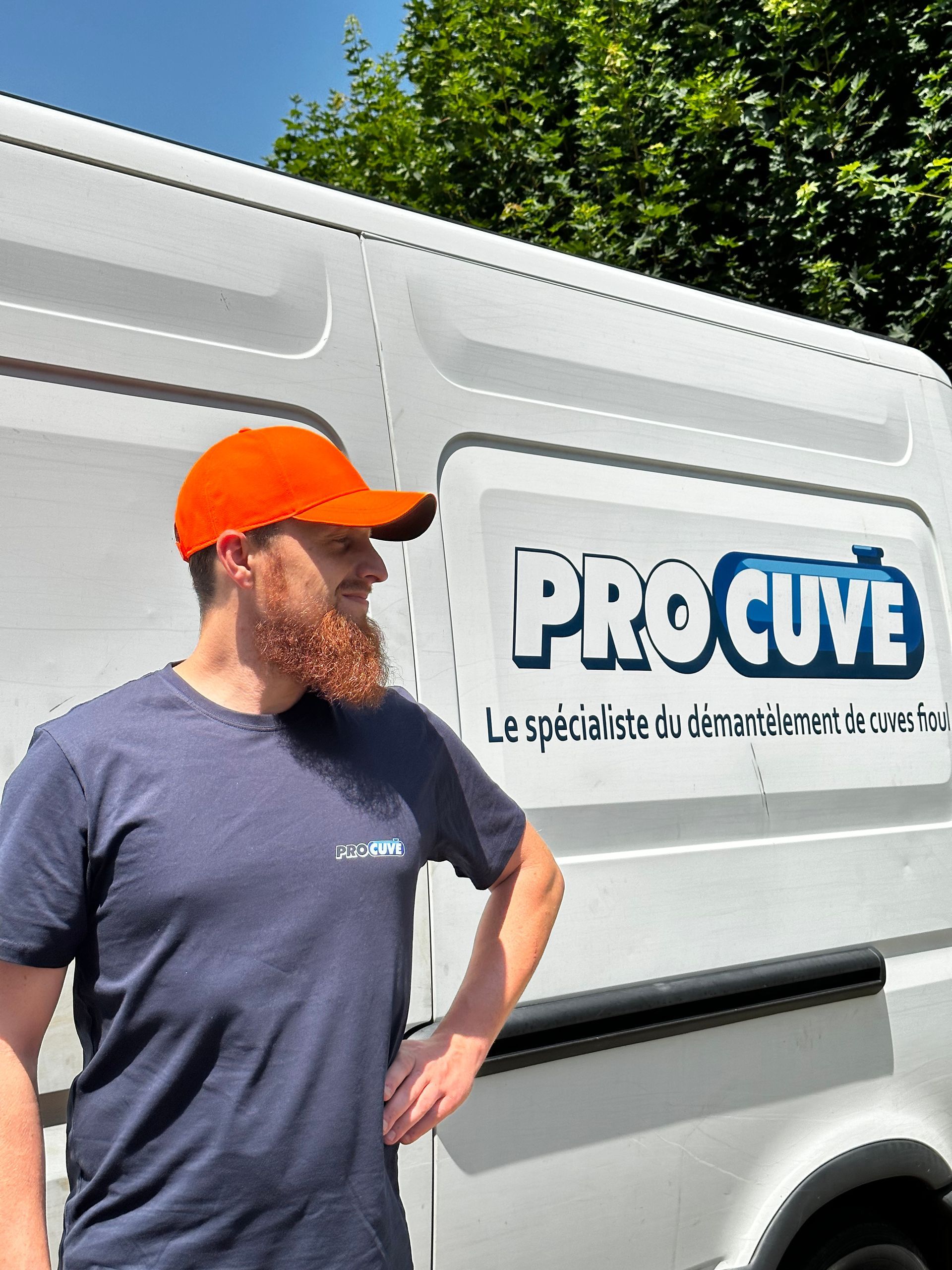 Professionnel de l'entreprise portant un teeshirt gris devant son véhicule