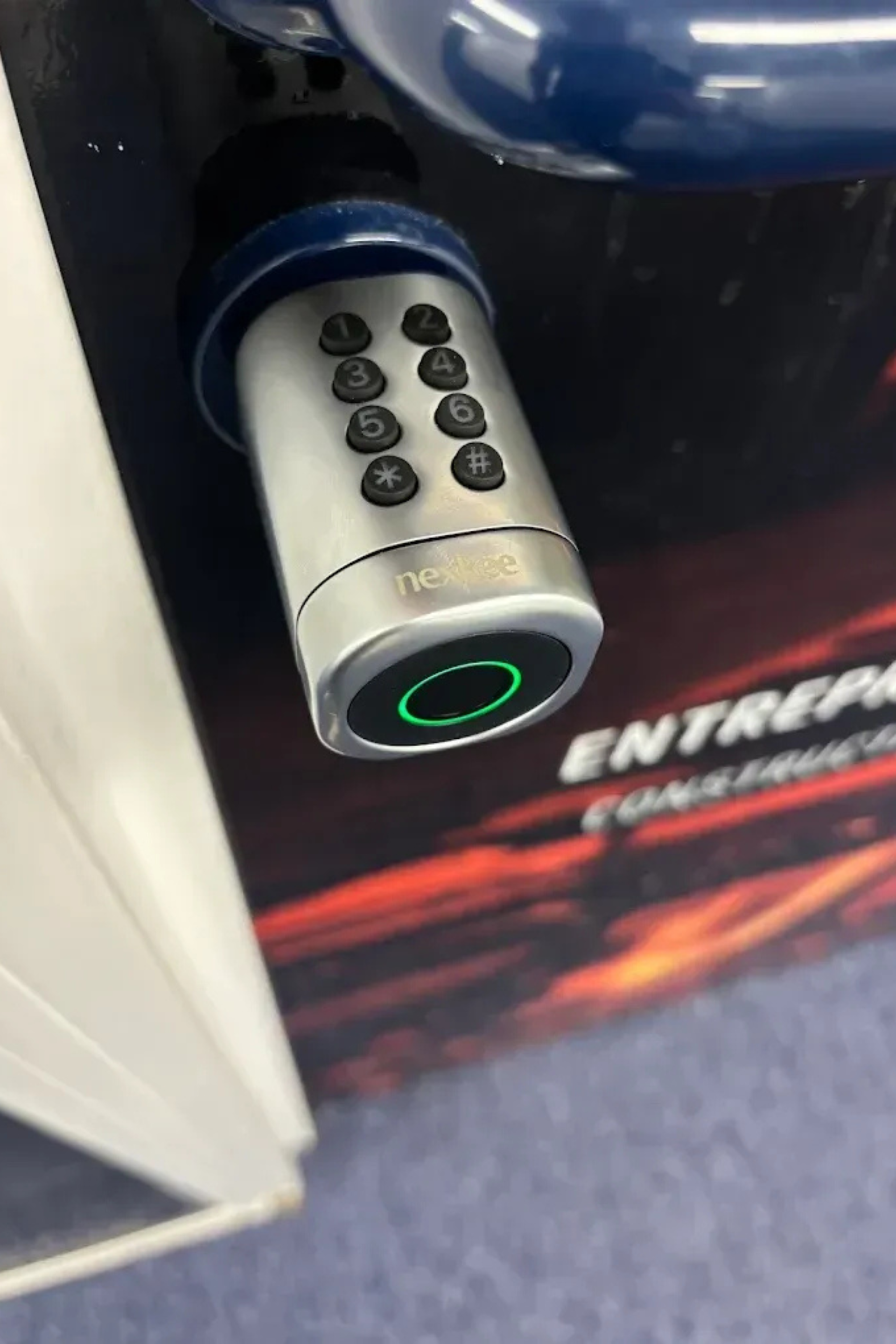 Un clavier argenté et un lecteur d'empreintes digitales sur une serrure bleue. Le lecteur s'allume en vert.