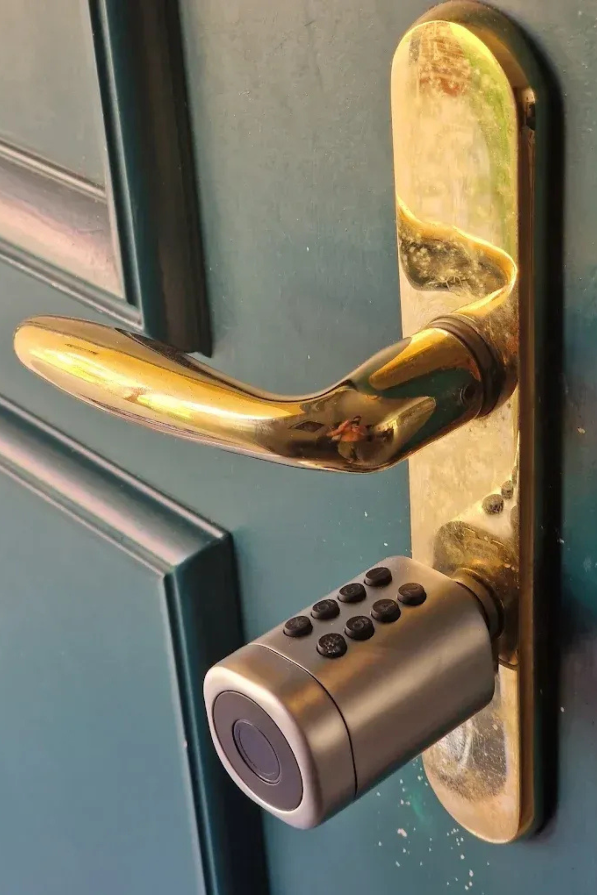 Poignée de porte en laiton avec serrure à clavier numérique sur une porte bleu sarcelle.