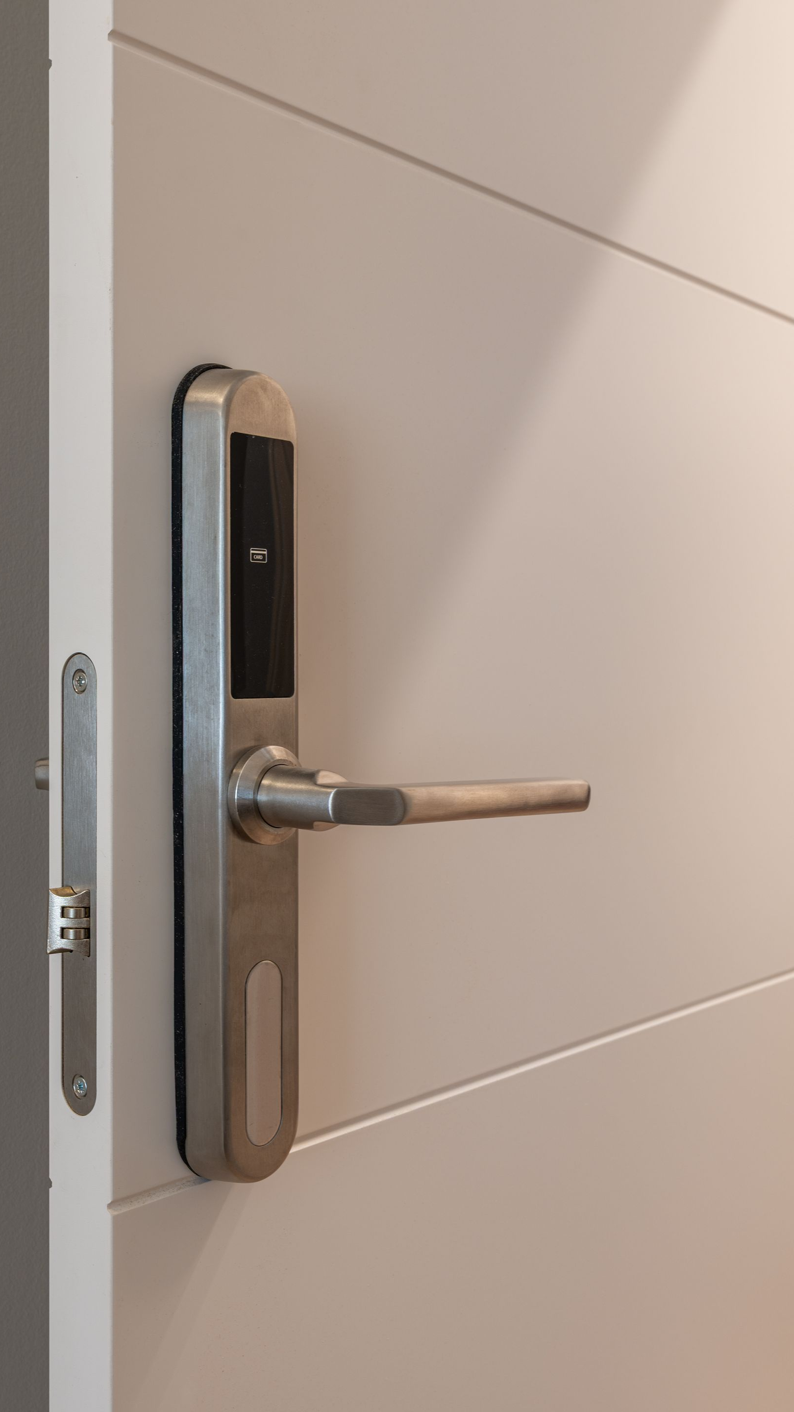 Serrure intelligente argentée sur une porte blanche avec une poignée argentée.