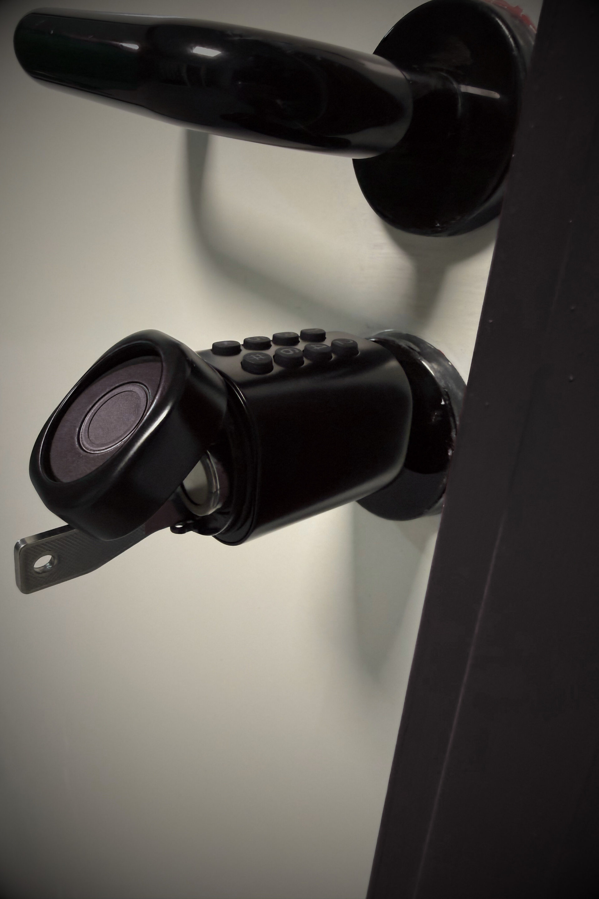 Porte de coffre-fort noire avec clé insérée dans une serrure à clavier et poignée en haut.