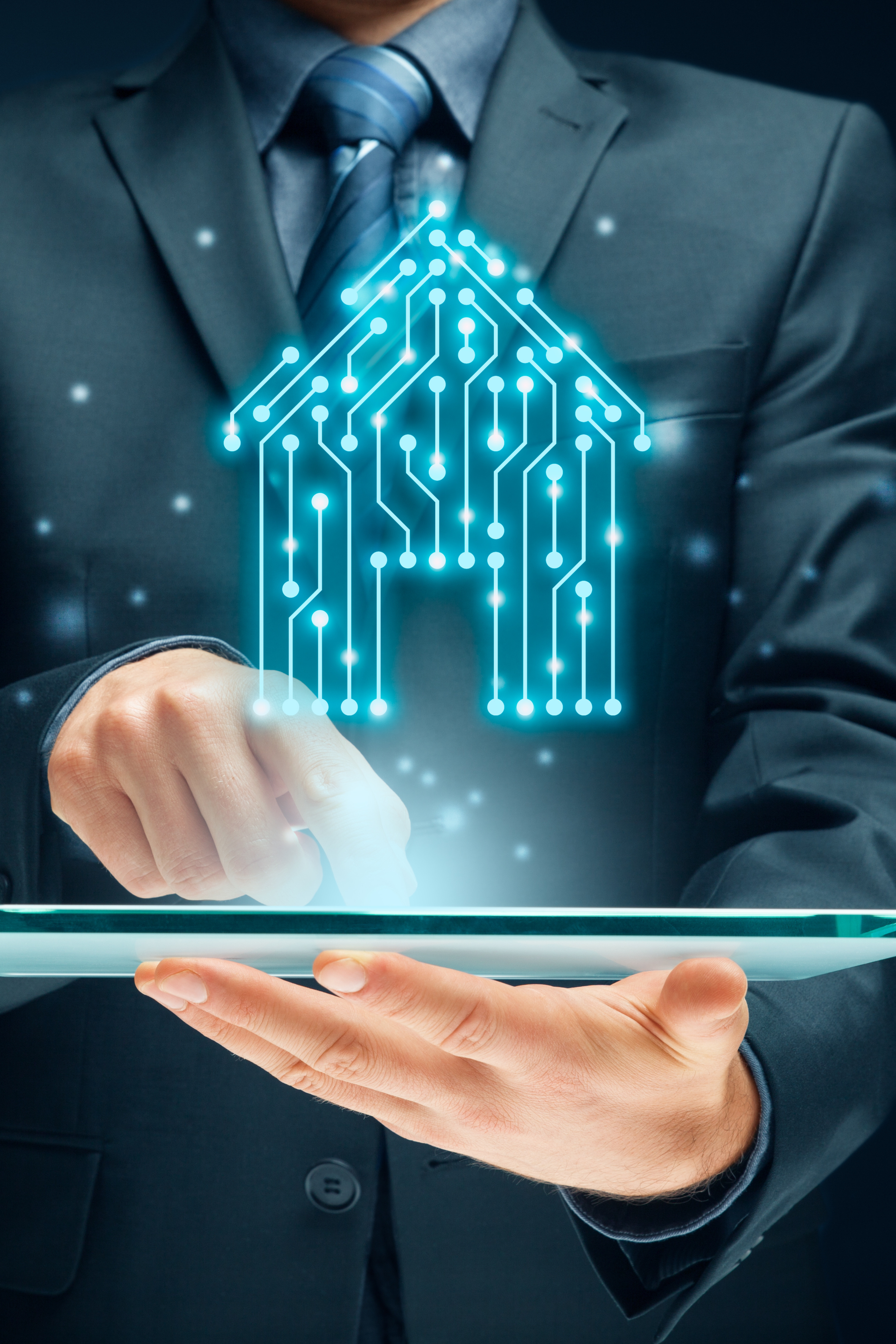 Homme en costume tenant une tablette avec un symbole de maison en circuit imprimé lumineux.