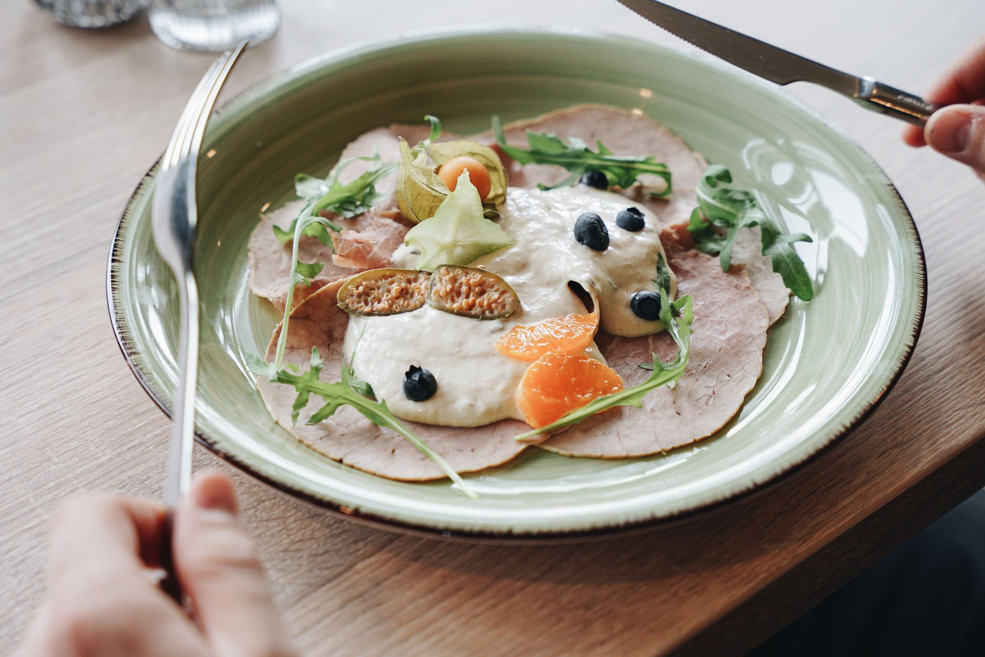 Eine Person kocht Würstchen in einer Bratpfanne mit einer Zange.