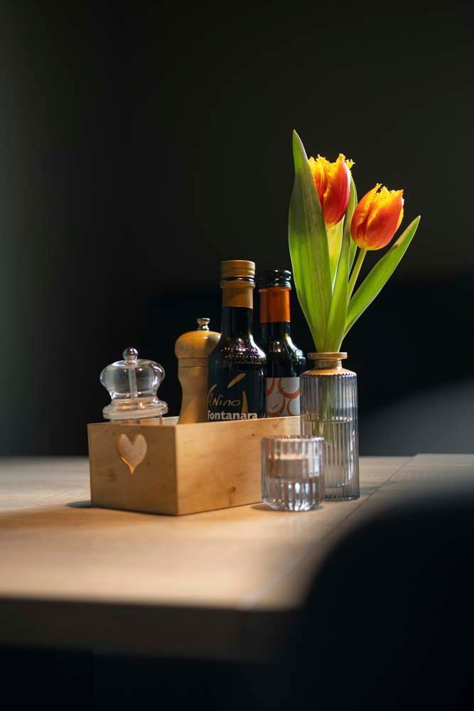 Ein Tisch mit Weinflaschen, Salz- und Pfefferstreuern und einer Vase mit Blumen.