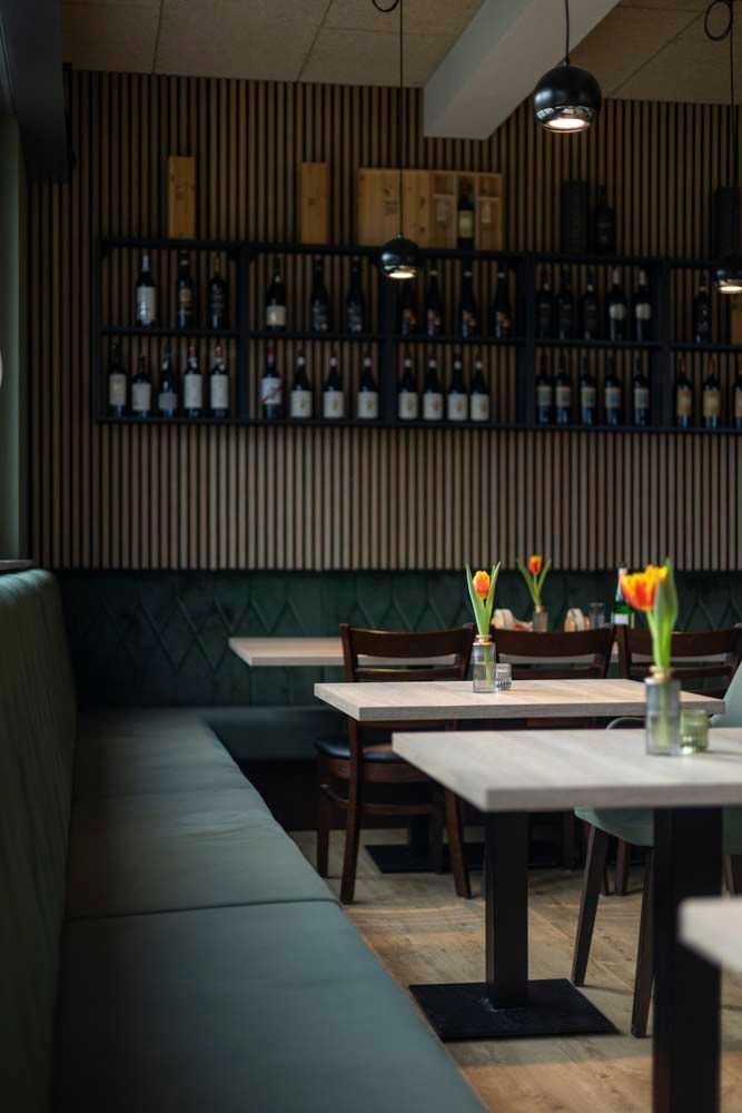 Ein Restaurant mit Tischen und Stühlen und Flaschen an der Wand.