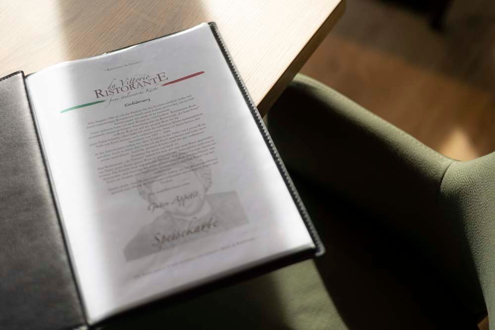 Auf einem grünen Stuhl liegt eine Speisekarte.