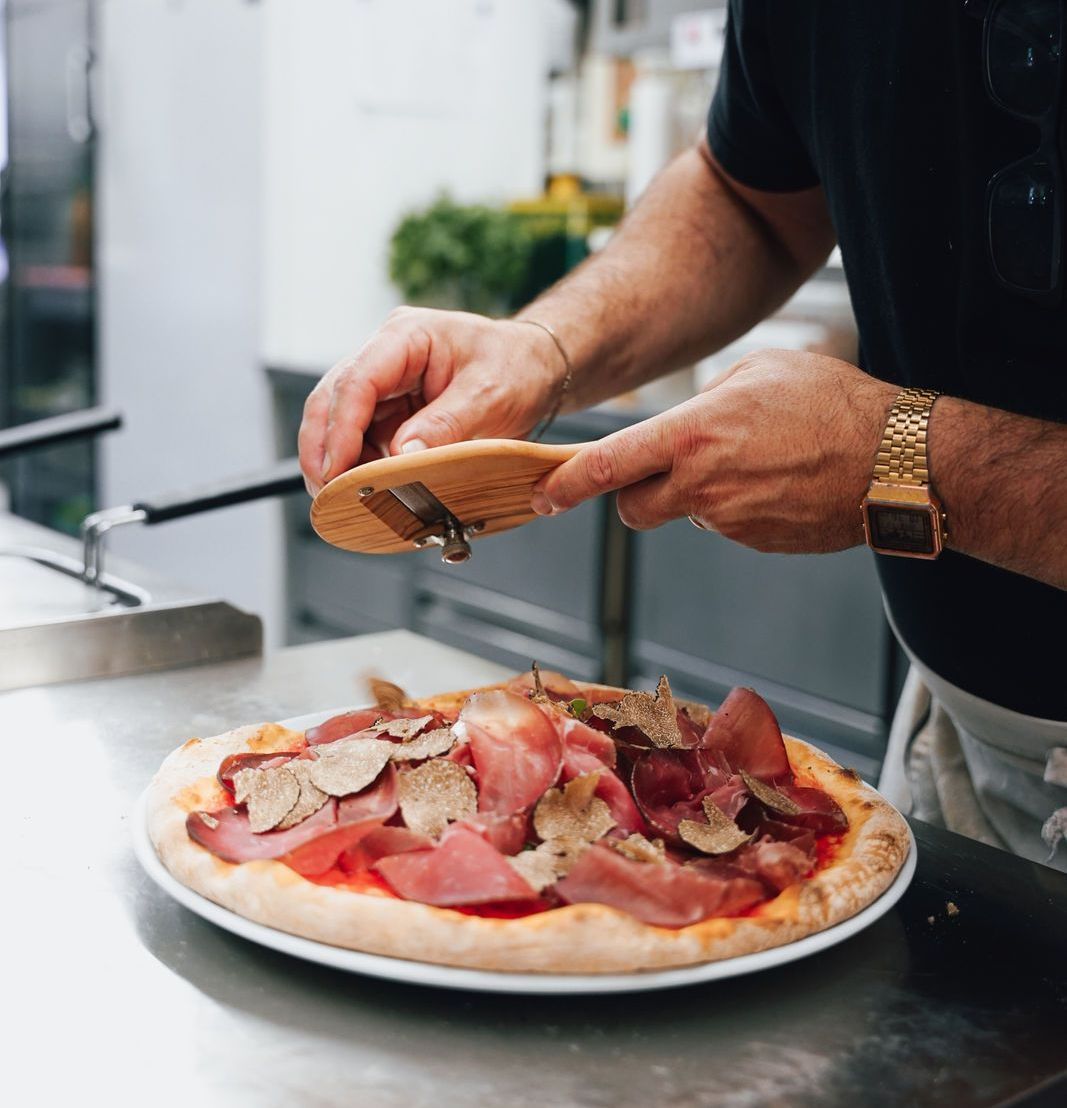 eine Nahaufnahme einer Pizza mit Fleisch und Soße auf einem Teller.