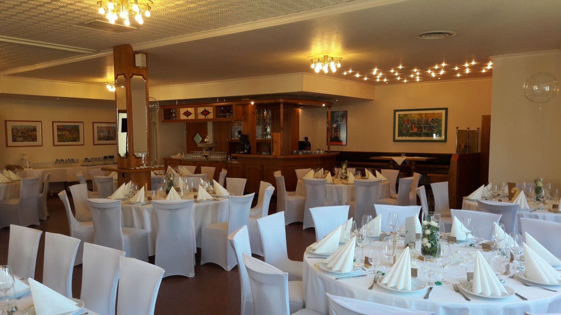 Runde, gedeckte Tische mit weißer Tischdecke