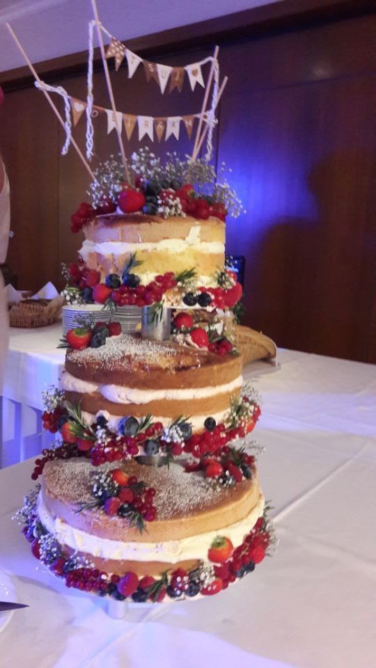 dreistöckige Hochzeitstorte , naked Cake mit Früchten, Blumendekoration und Dekobanner