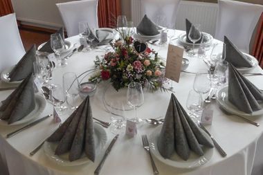 Gedeckter Tisch mit grauen Servietten und buntem Blumenstrauß in der Mitte