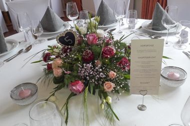 Gedeckter Tisch mit rose Blumenstrauß in der Mitte und Menükarte